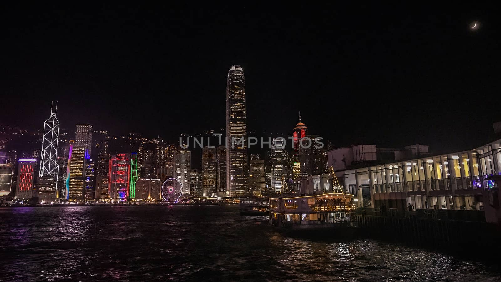 Hong Kong cityscape, building and ferry boat near victoria river in the evening