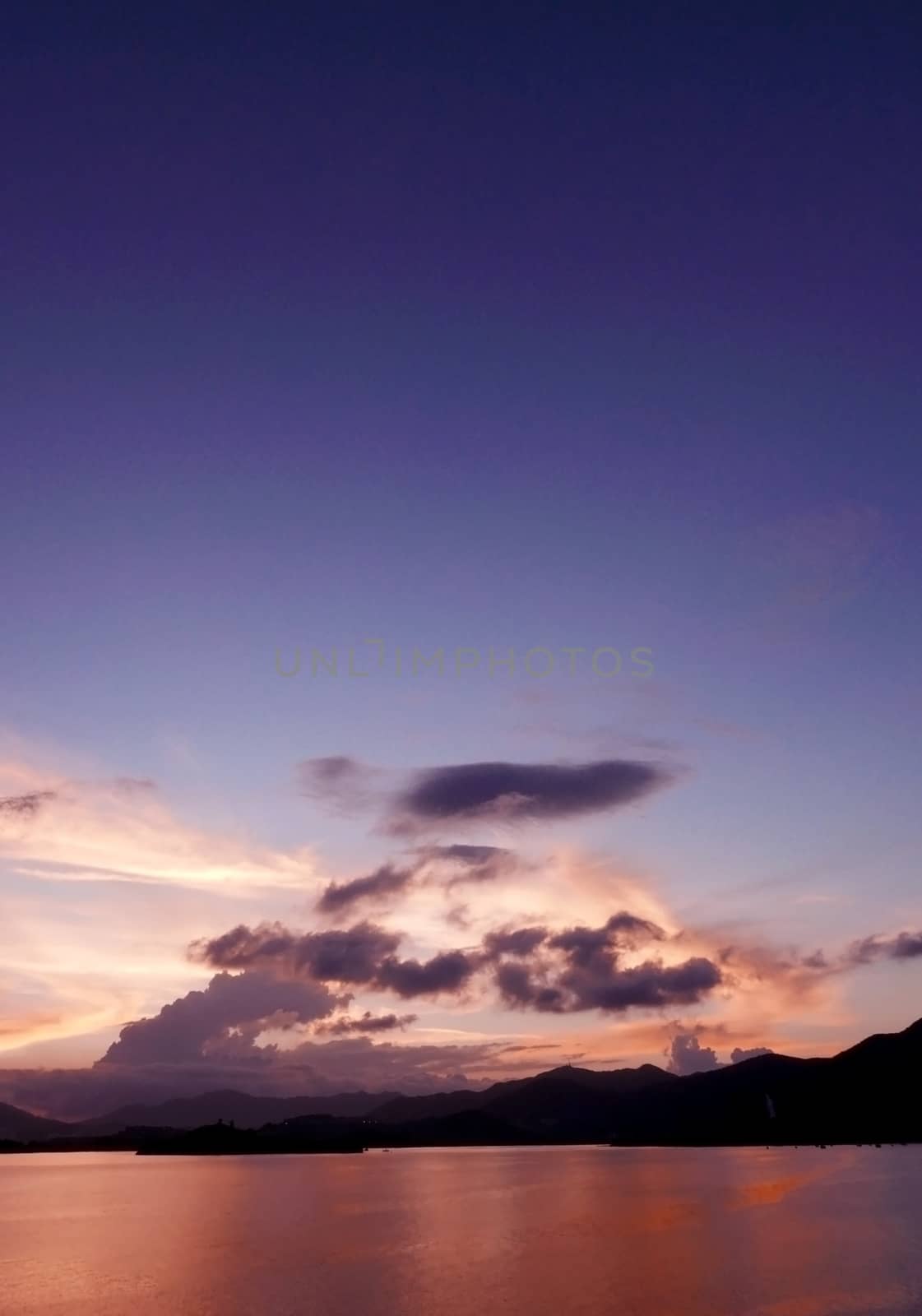 Vertical mountain, cloudscape, dramatic sky and the ocean at sunset