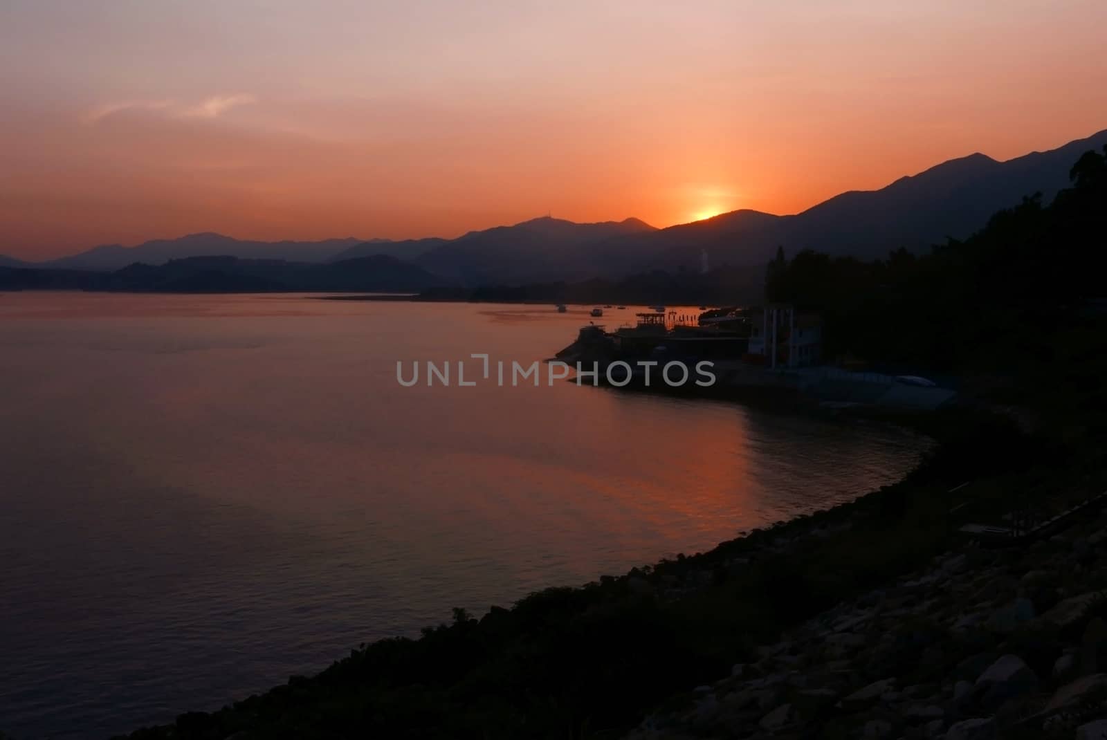 The silhouette of boats, sun, mountain and sea at sunset