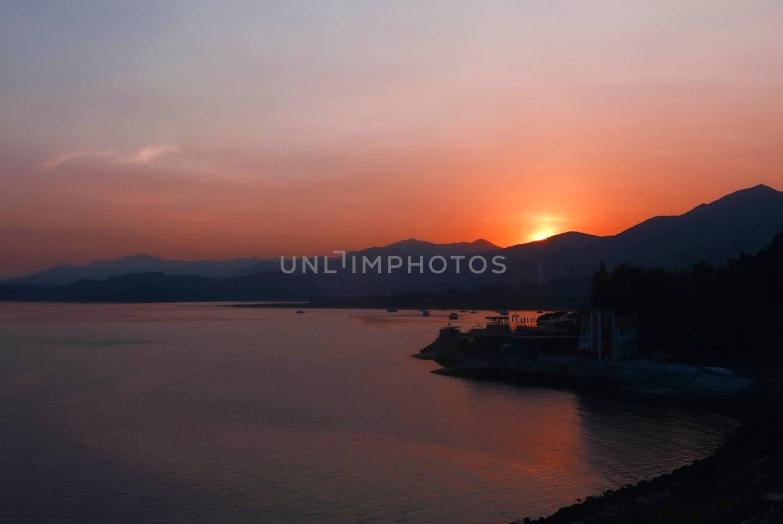 The silhouette of mountain, boats and lake at sunset