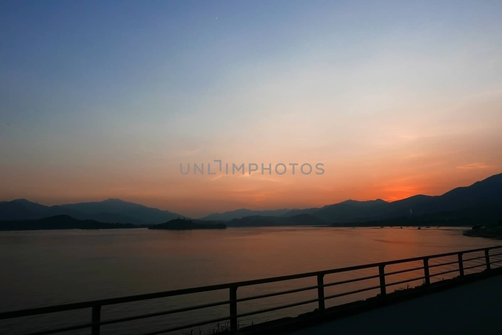 footpath, fence, sea, lake and mountain at sunset