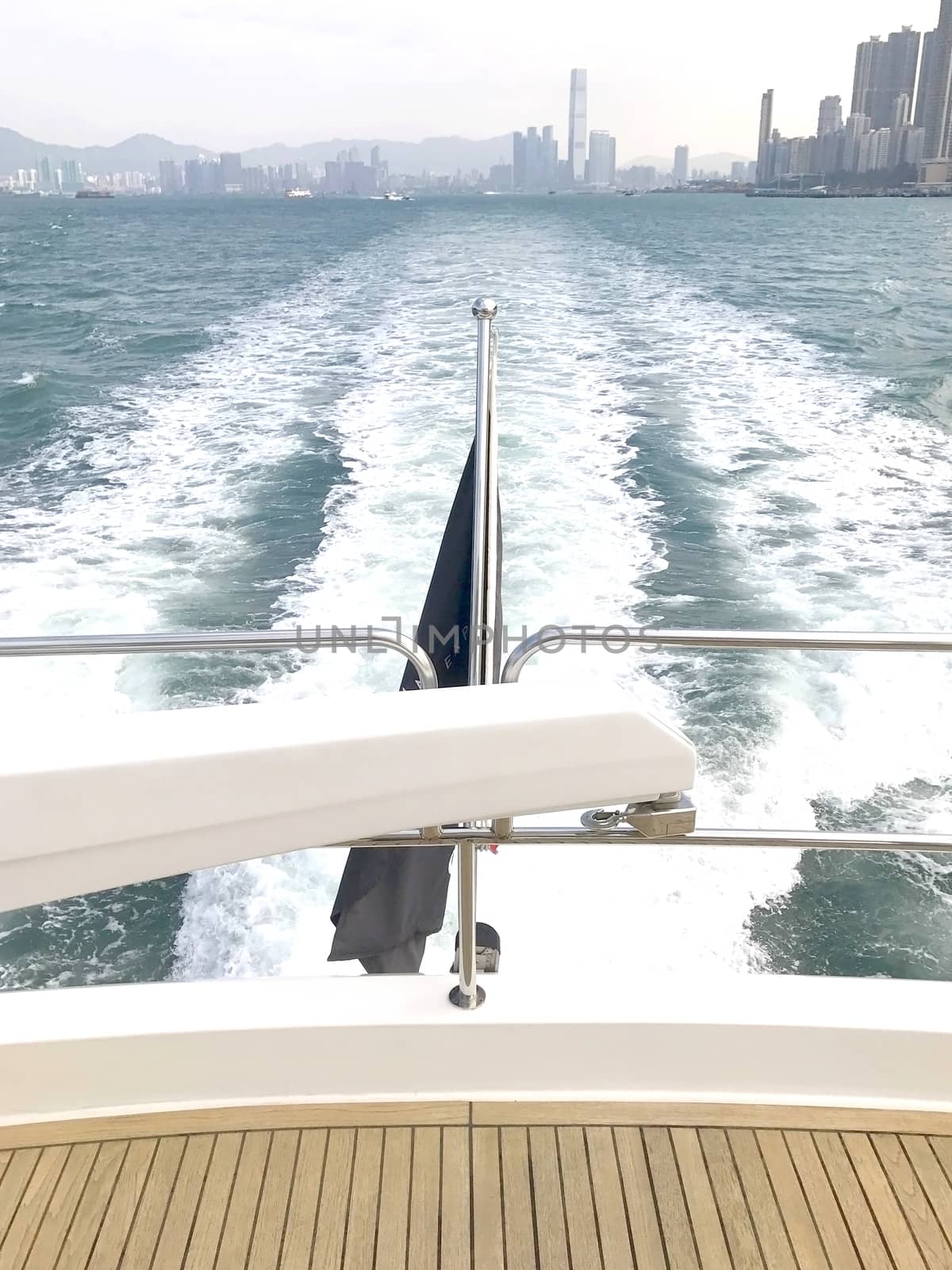 The end of white yacht with flag and Hong Kong building