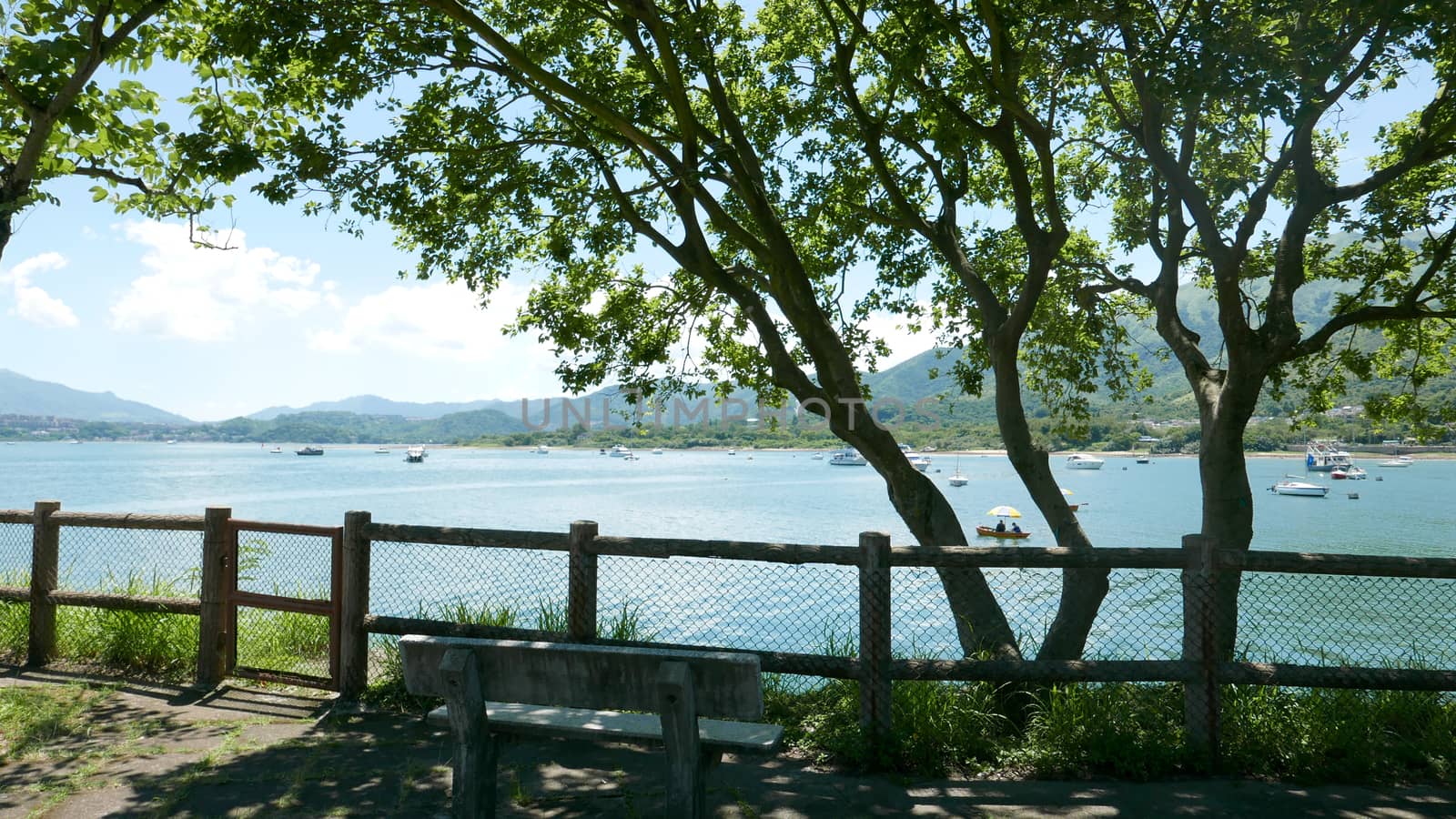 Outdoor bench, trees, mountain and fishing boats by cougarsan