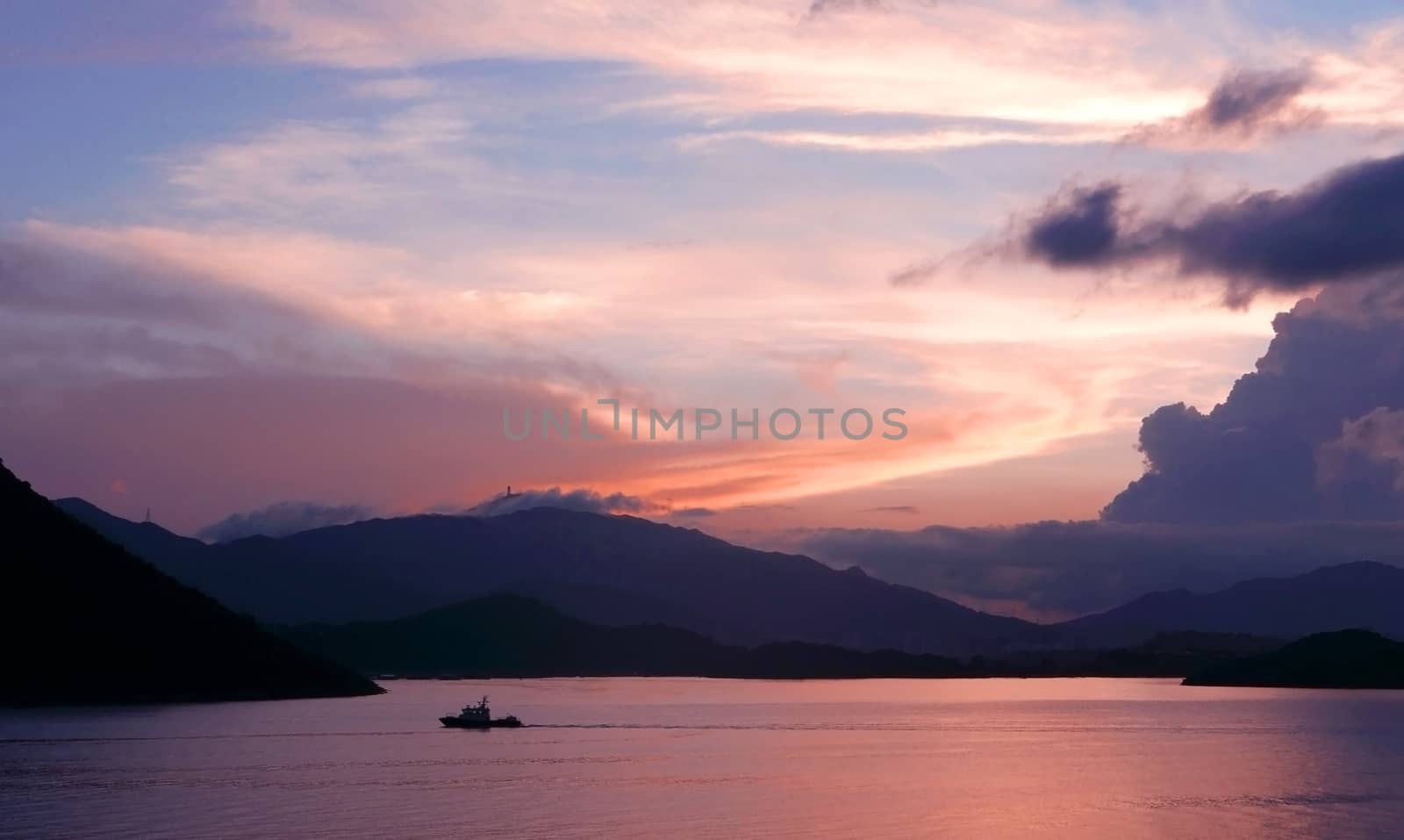 mountain, dramatic sky, boat on the sea at sunset