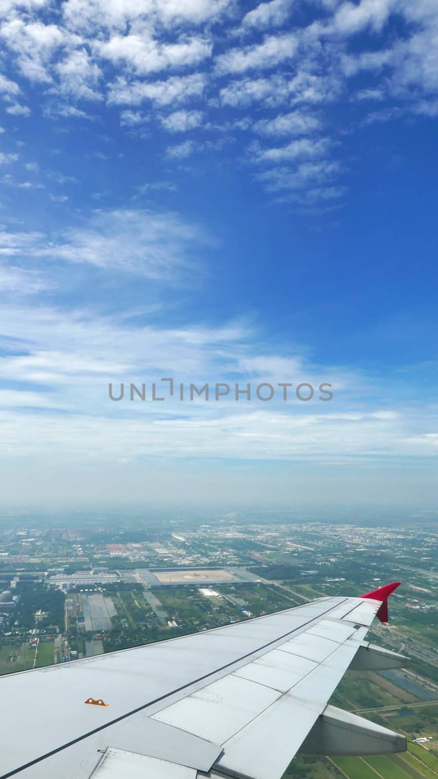 Vertical wing of airplane with green land and blue sky