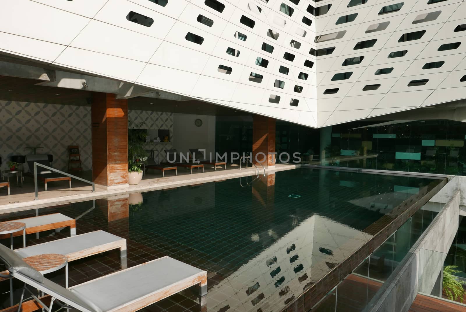 The swimming pool in the hotel with reflection suntan chair