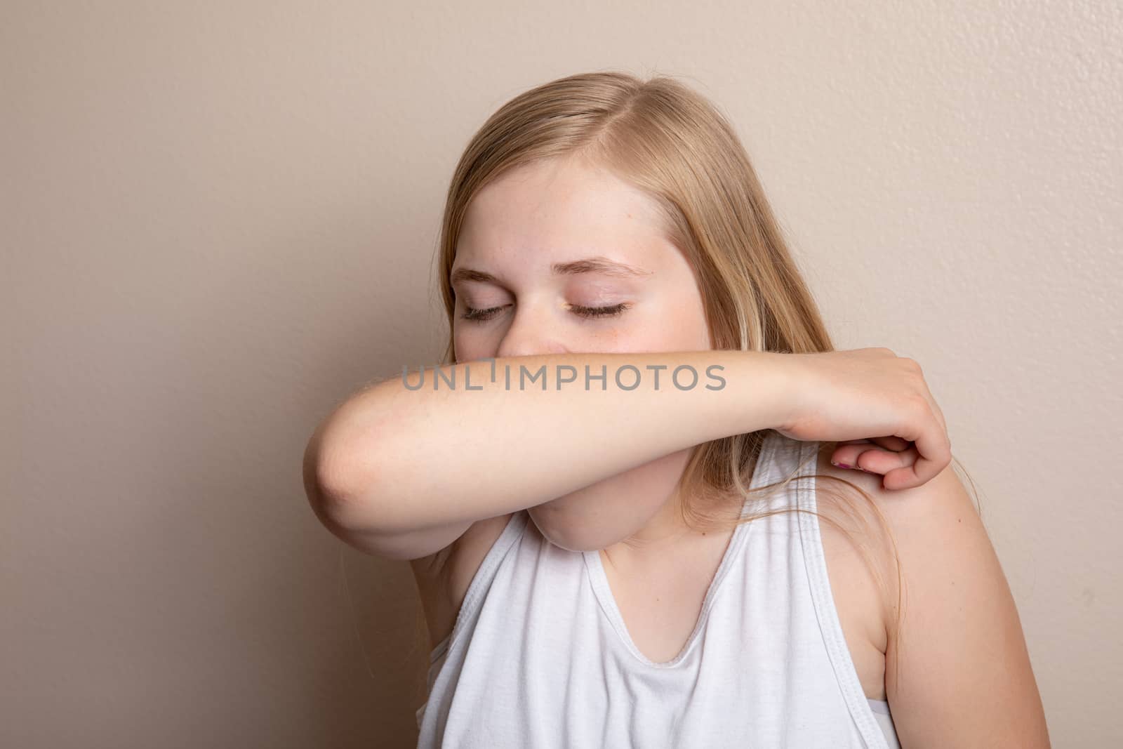 girl trying to prevent the spread of disease by coughing into her elbow