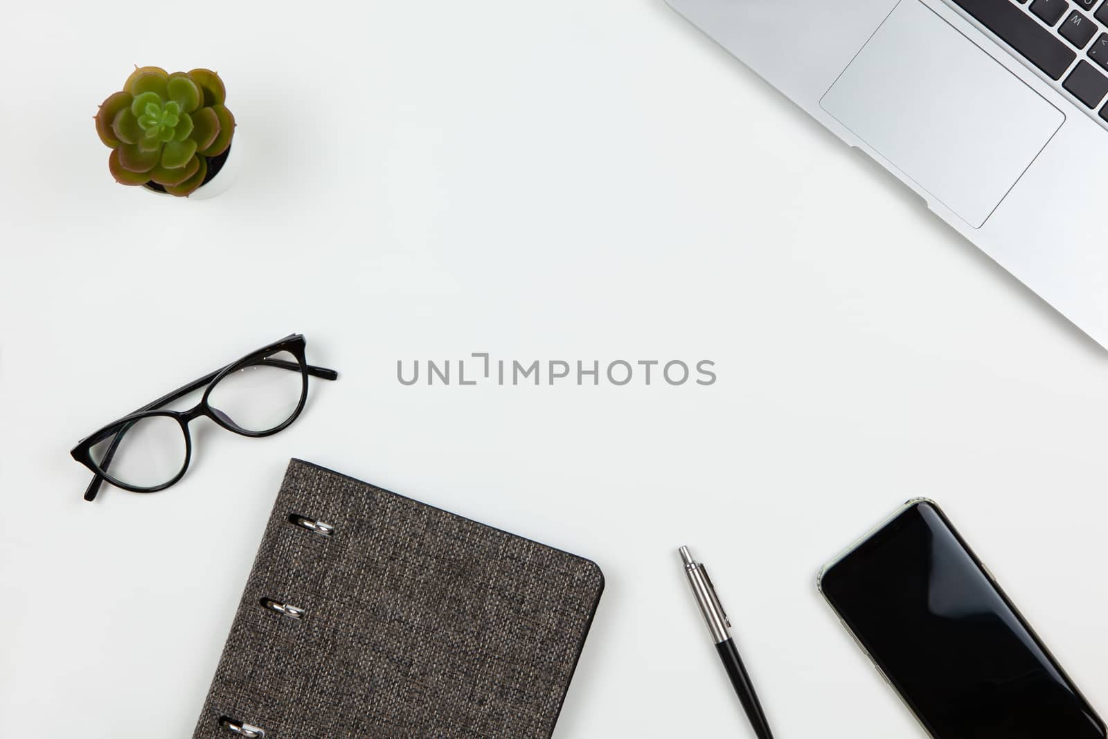 Modern unisex working space, top view. Notepad, pen, cactus, smartphone, glasses on white background, copy space, flat lay. Desktop of freelancer. Work from home, stay home concept by ALLUNEED