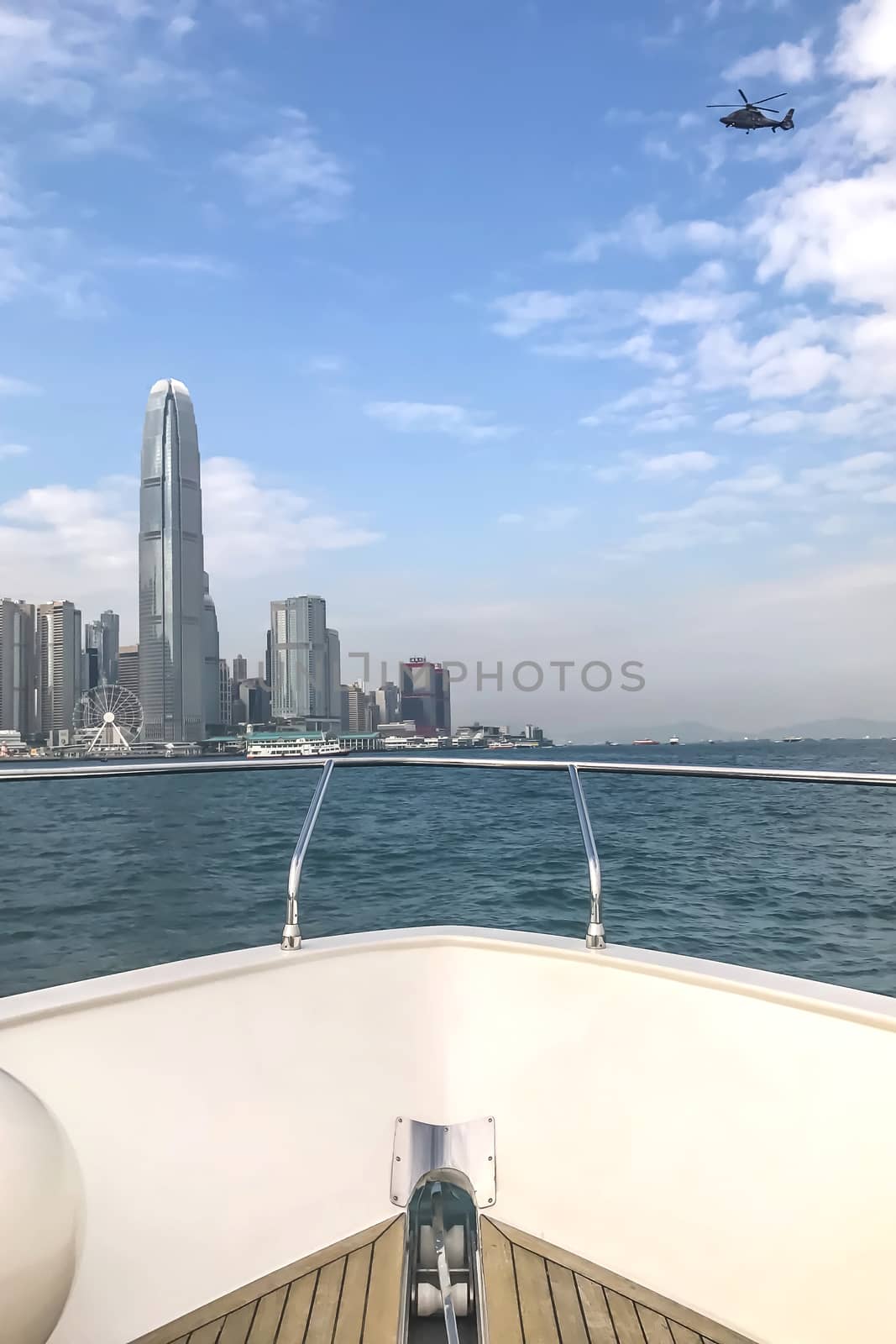 The head of white yacht, Hong Kong downtown building and helicopter in sunny day