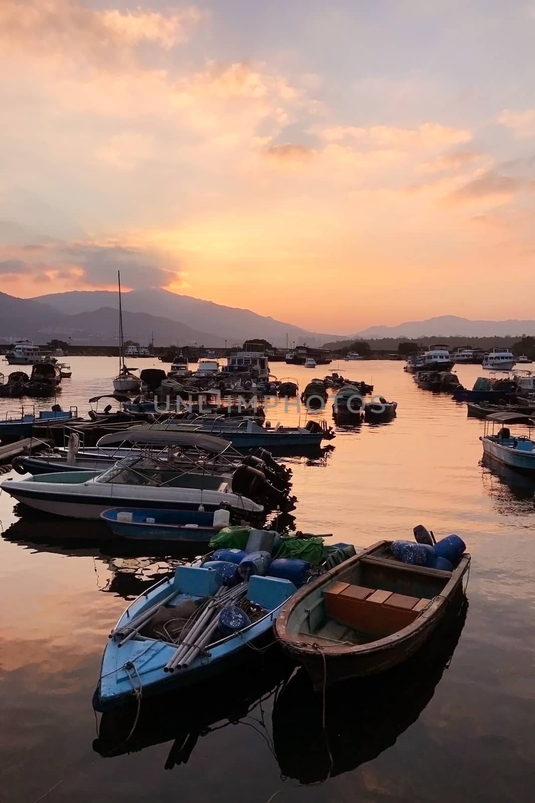 Fishing boat in wharf and the gradient orange sky at sunset