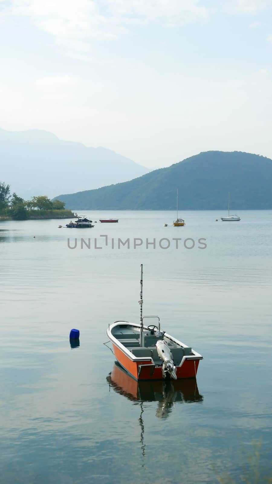 Vertical red fishing boat on peaceful lake in day time