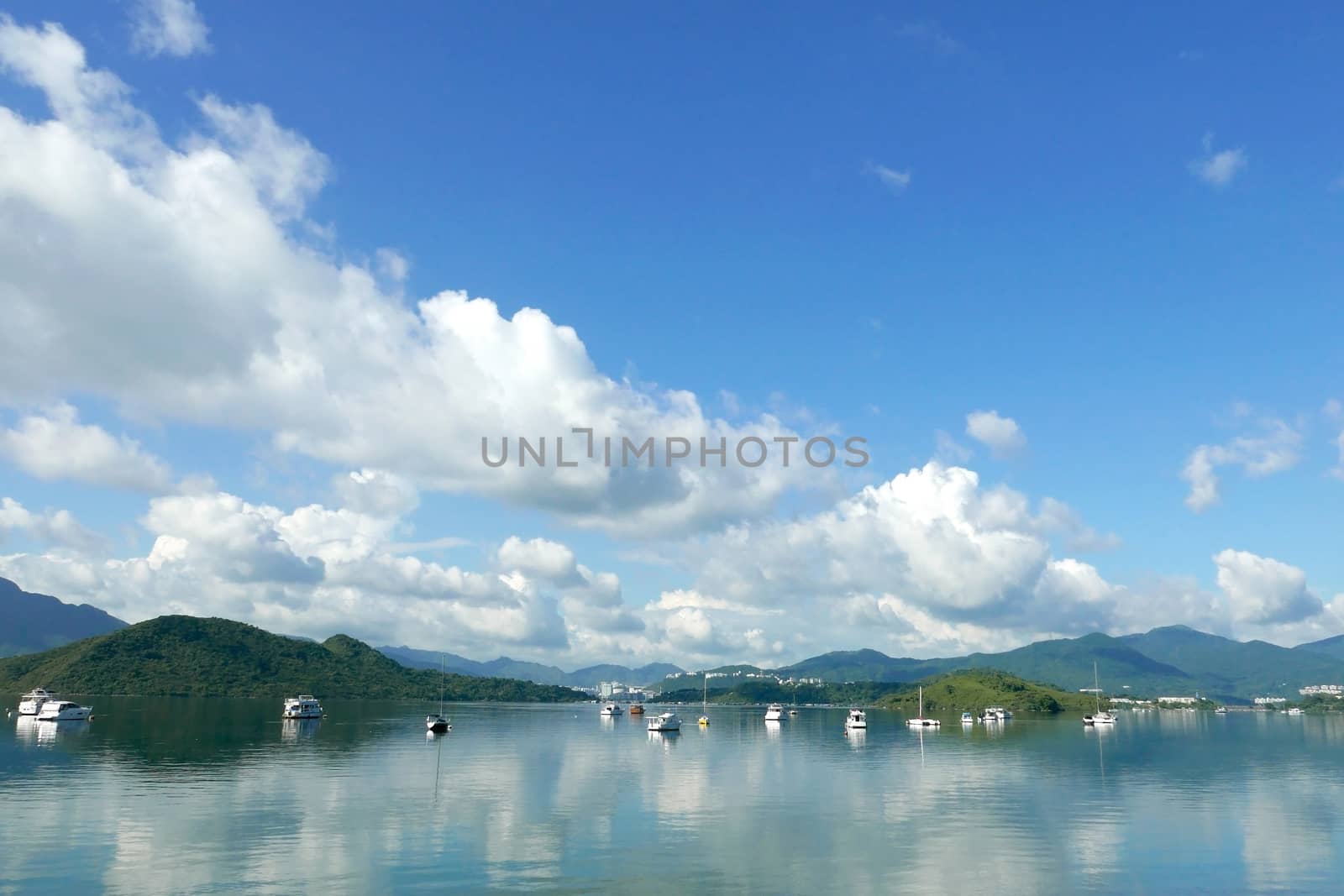 Boats, white clouds, lake and blue sky with reflection shadow by cougarsan