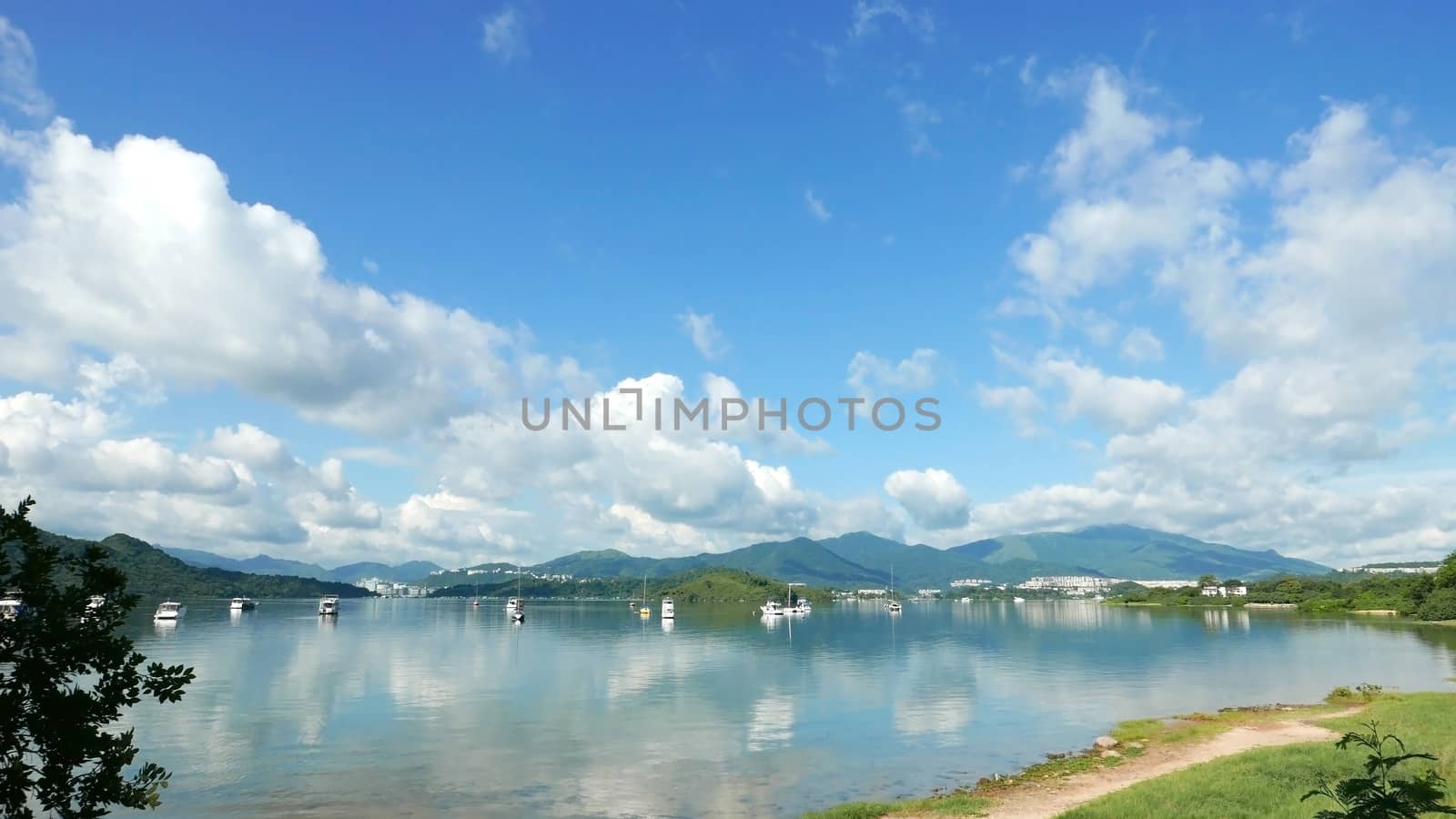 Boats, white clouds, lake and blue sky with reflection shadow