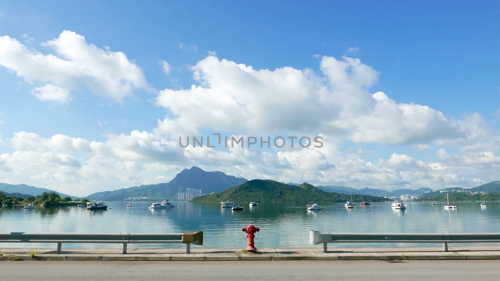 Road, red water pump, boat, tree, lake, blue sky and the white cloud