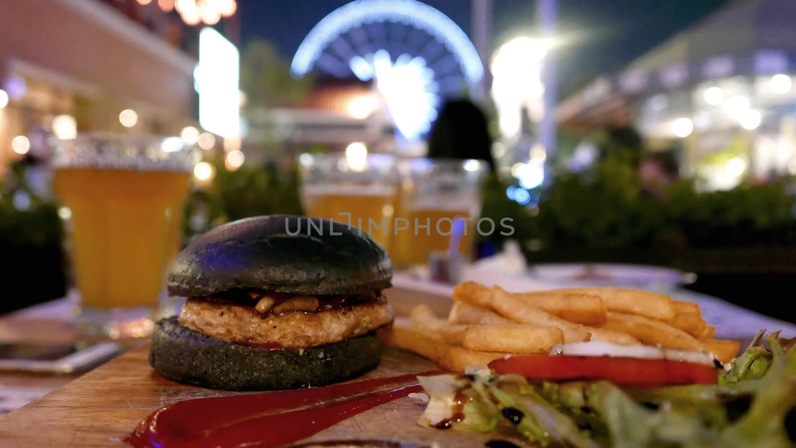 Black burger, fries and drink meal dinner set at night by cougarsan