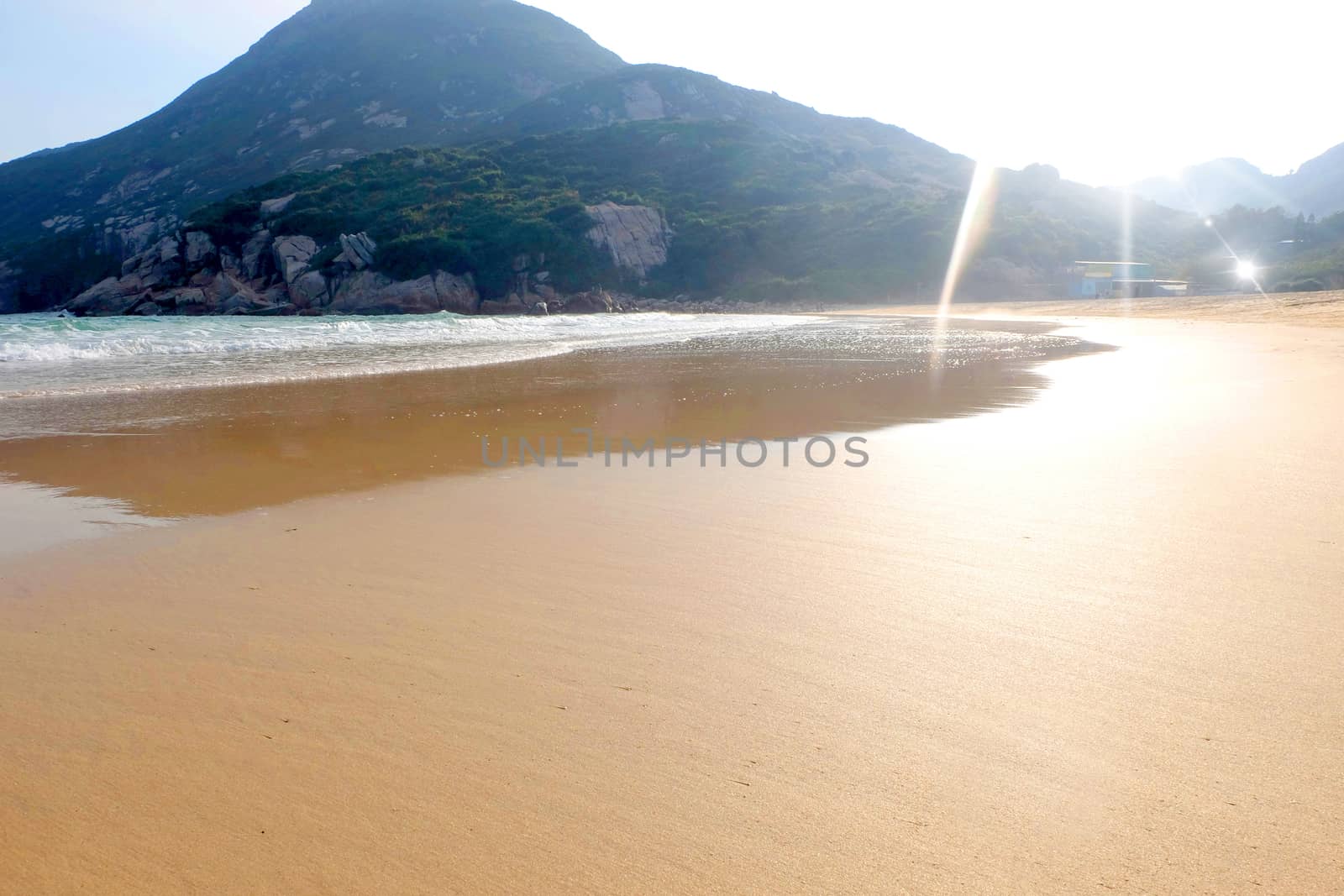 Sand and waves on the beach near the mountain