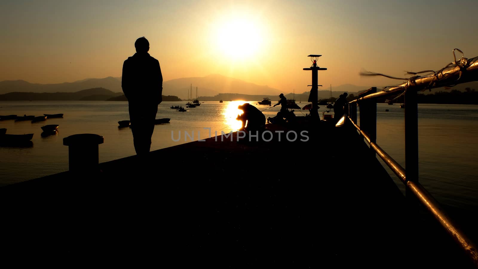 Shadow of the small pier and man at sunset