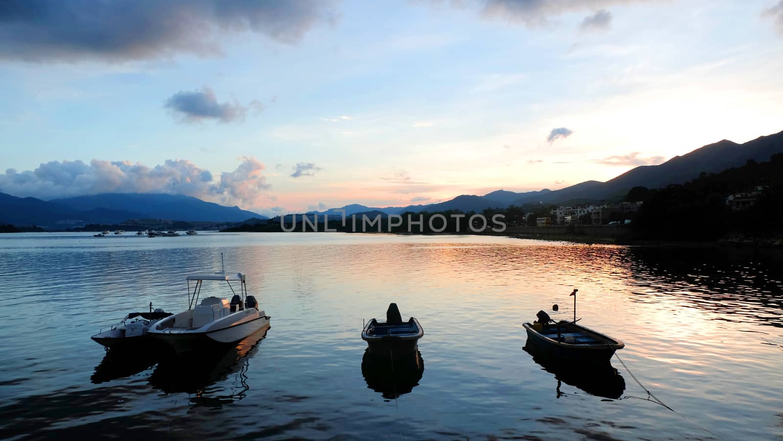 The silhouette of fishing boat and pier on lake with mountain at sunset by cougarsan