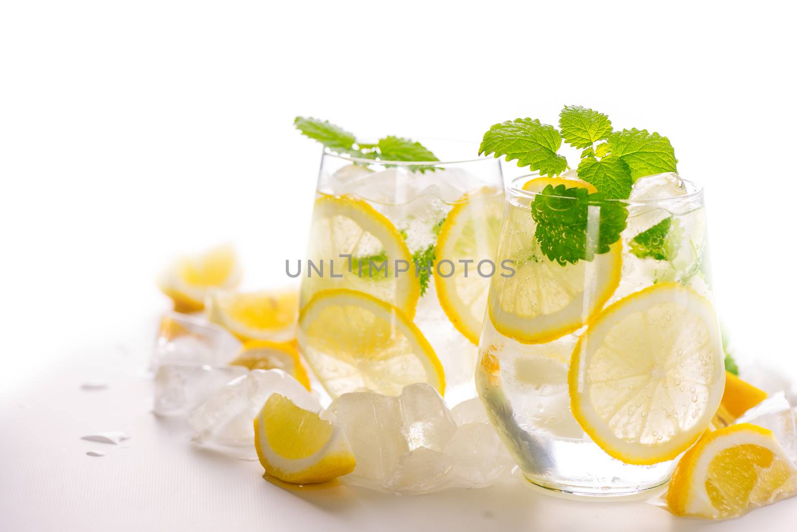 Lemonade drink in a glass: water, ice, lemon slice and mint on white background