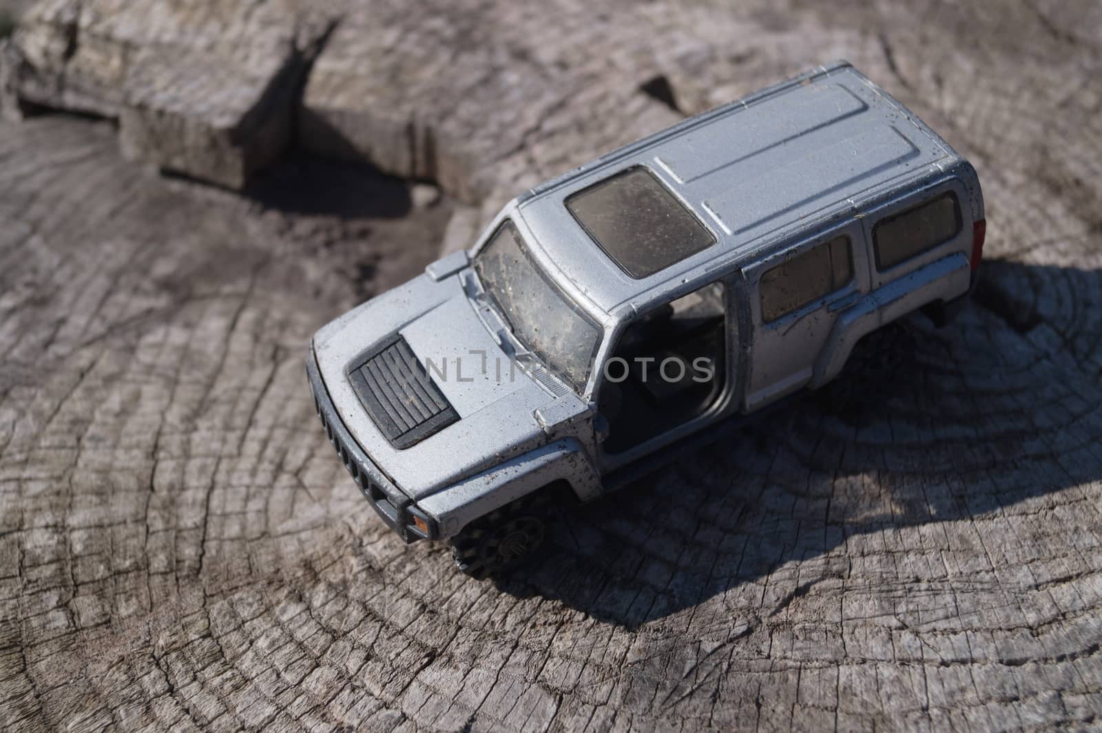 A silver toy car on wooden background. This is jeep offroad SUV made in metal