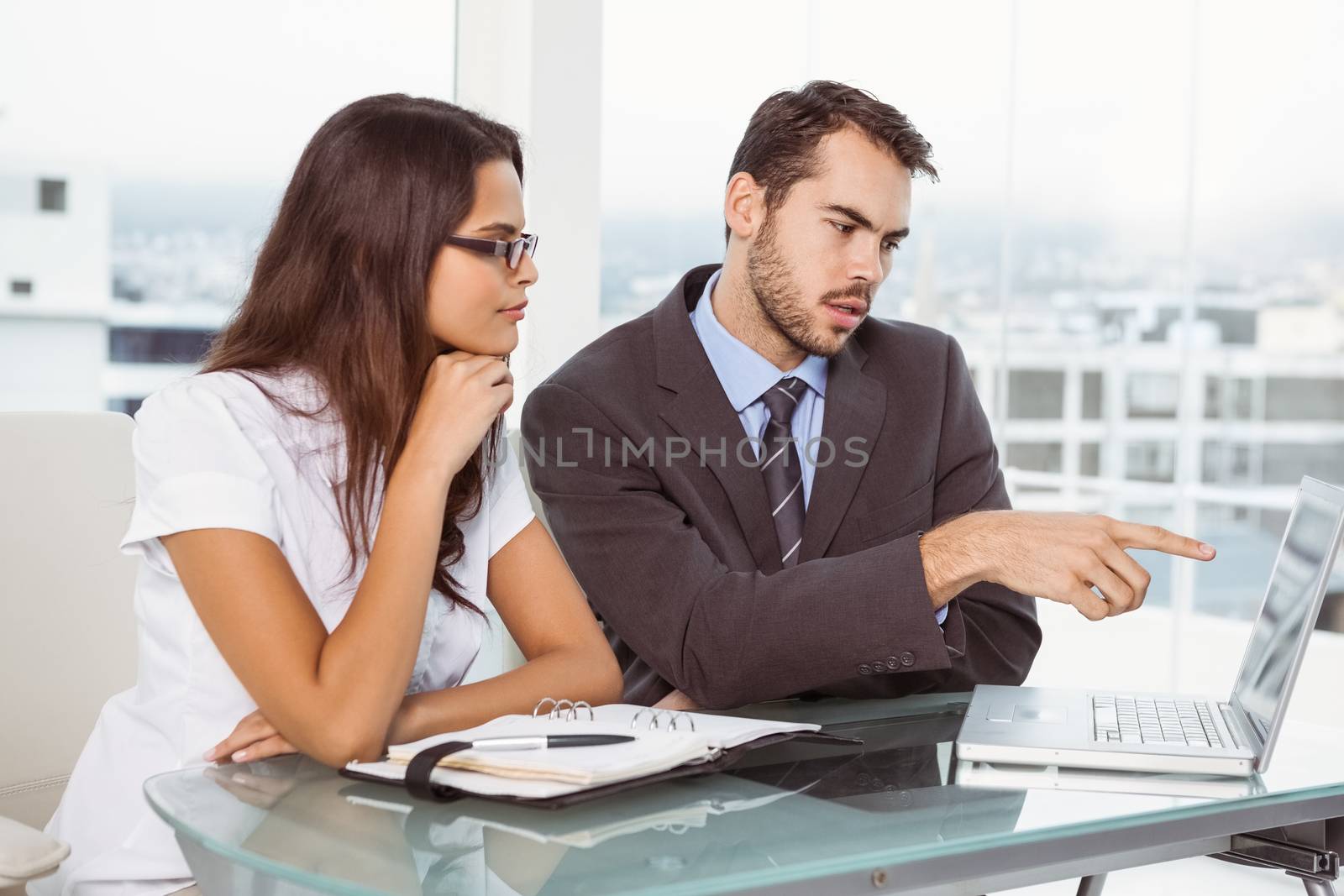 Two young business people using laptop in office