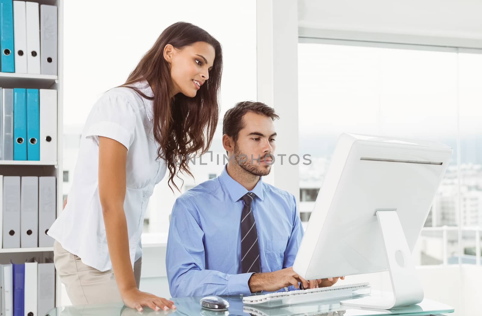 Two young business people using computer in office