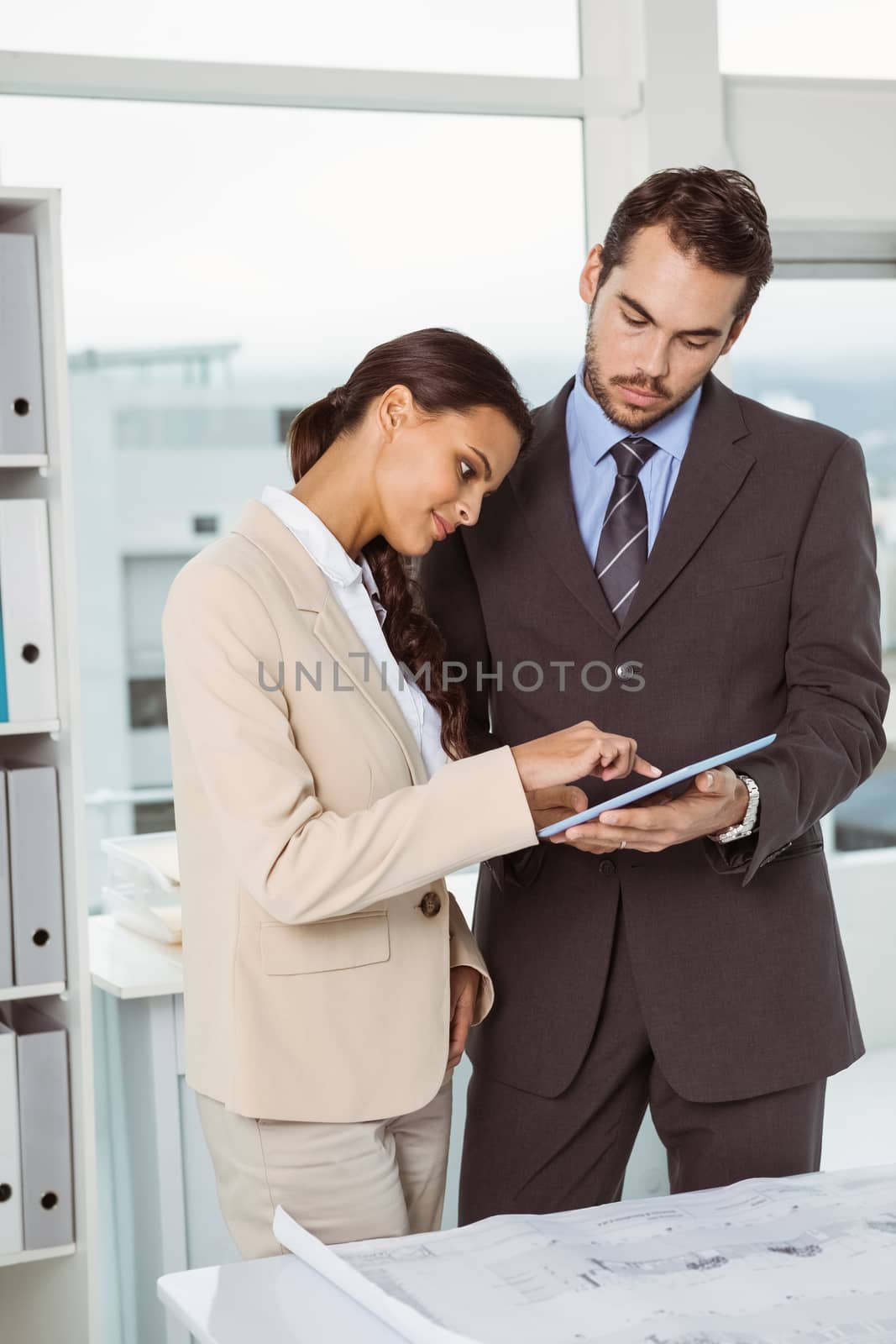 Two young business people using digital tablet in the office
