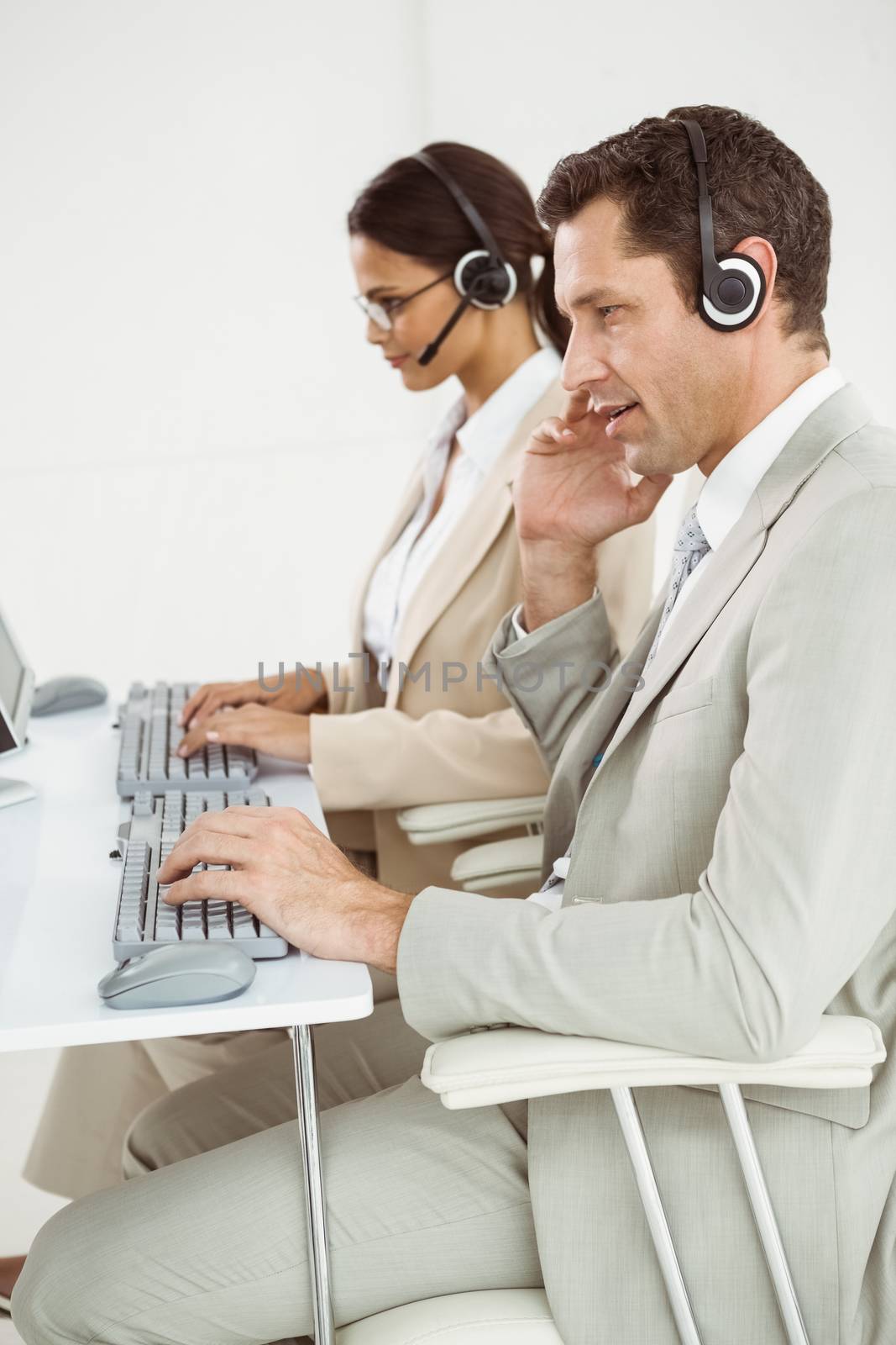 Business people with headsets using computers by Wavebreakmedia
