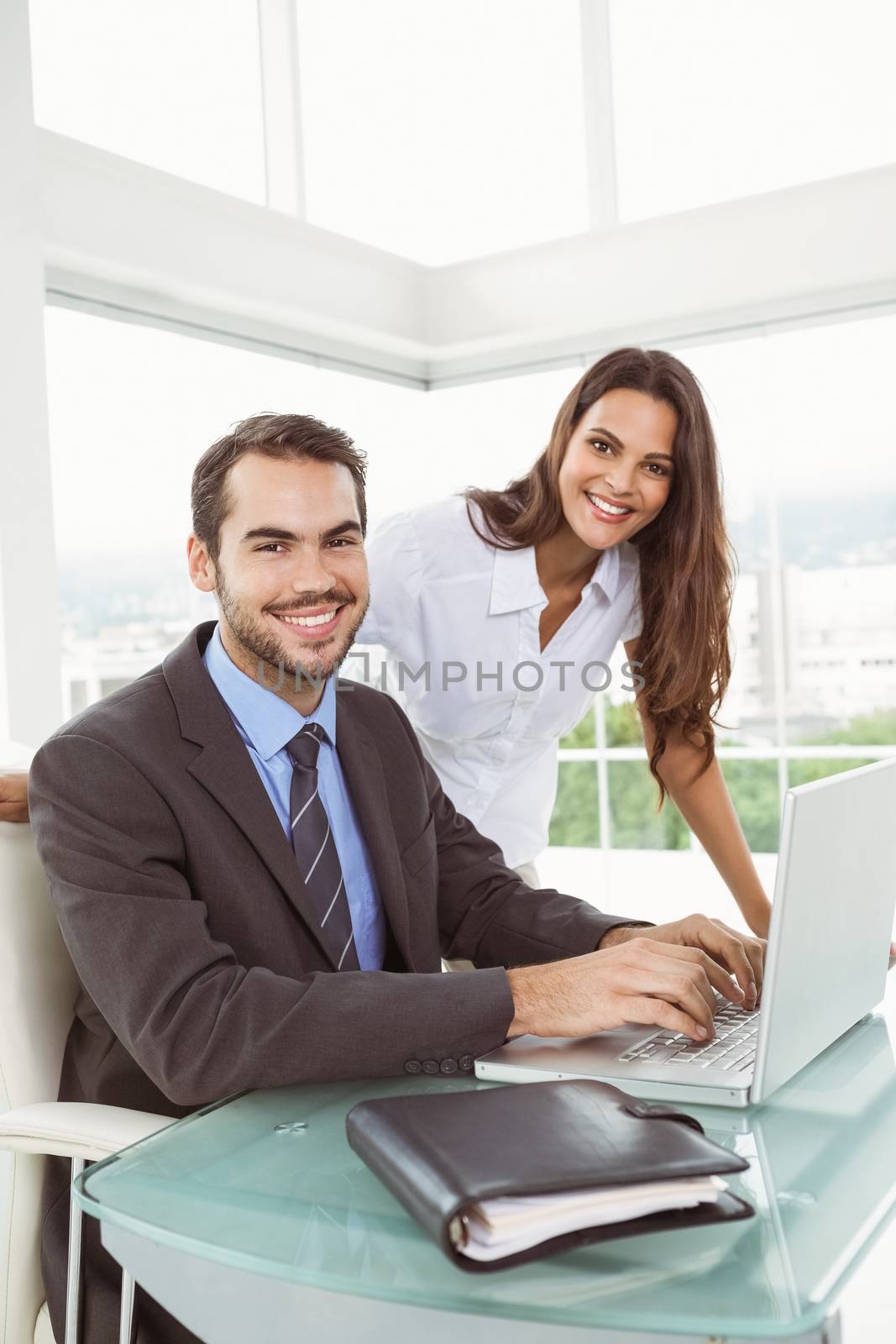 Portrait of two young business people using laptop in office