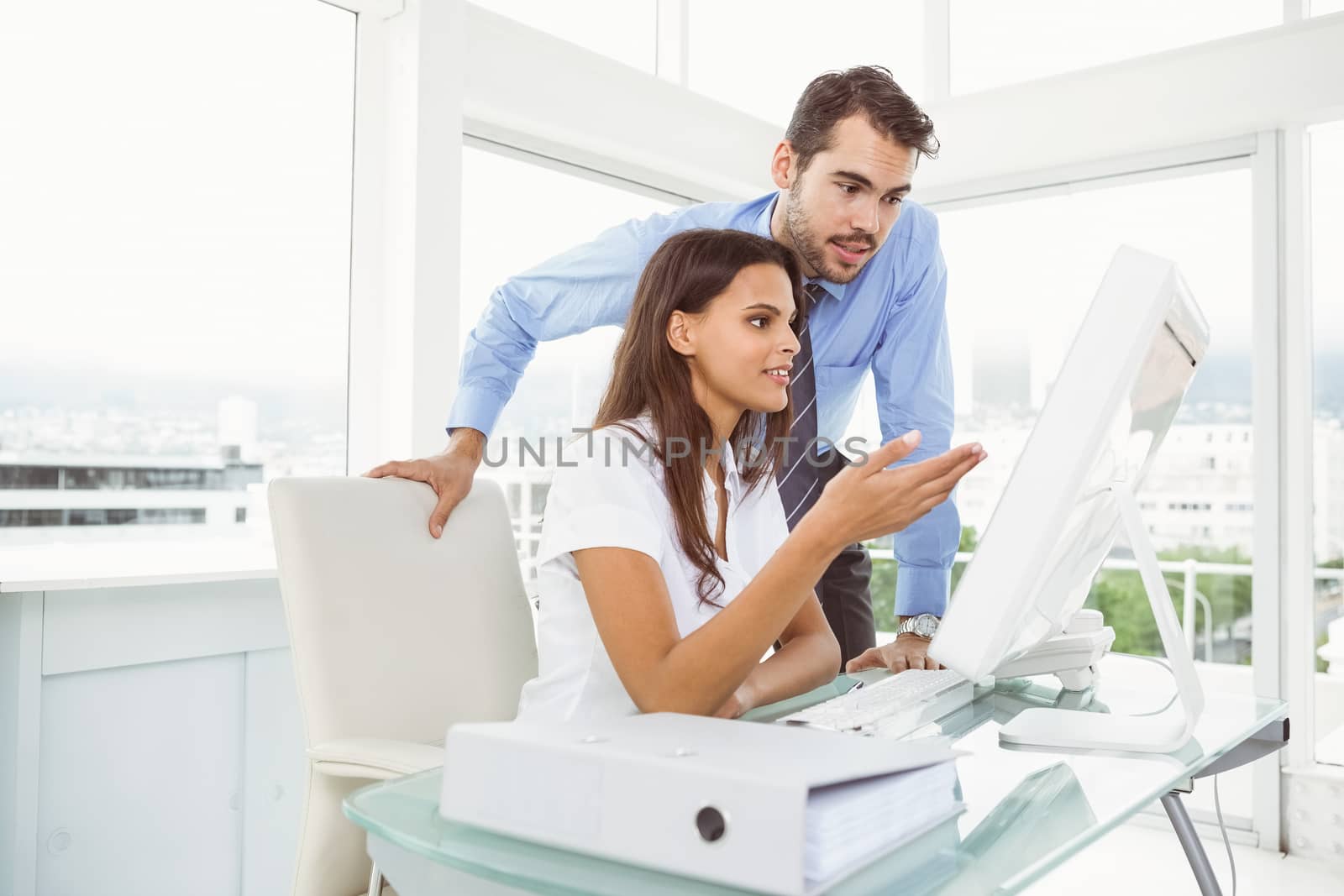 Two young business people using computer in office