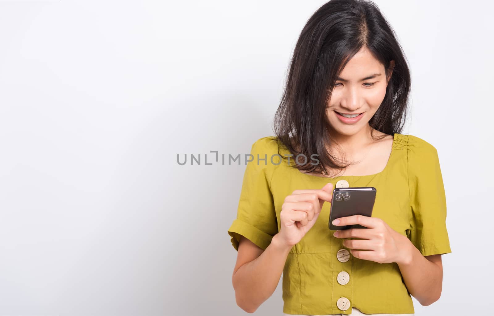 Portrait Asian beautiful happy young woman standing smile holding using mobile smart phone looking to smartphone, shoot the photo in a studio on a white background, There was copy space