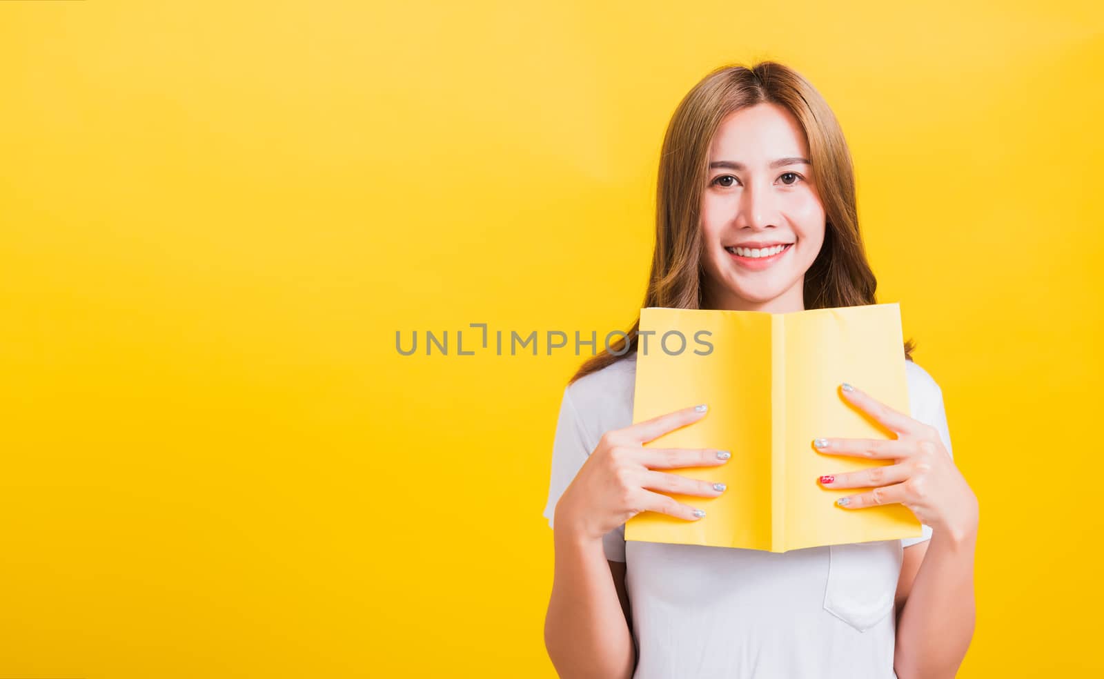 woman stands holding yellow book or diary by Sorapop