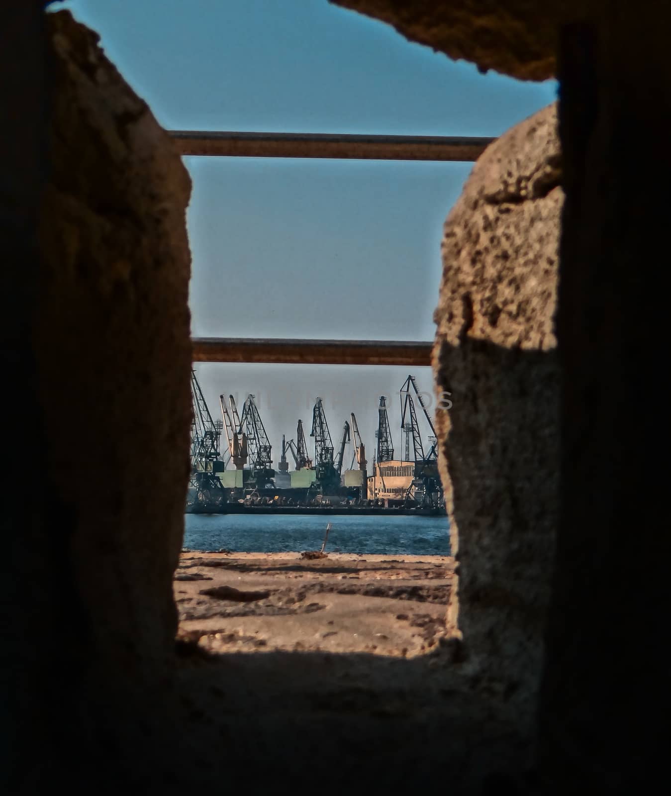 An industrial landscape at the coast of the sea, caught through a stone hole. by justbrotography