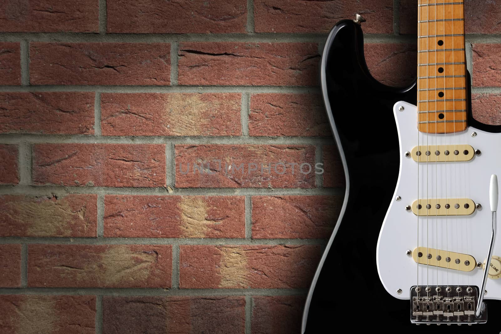 Retro black and white electric guitar on brick background with copy space by VivacityImages