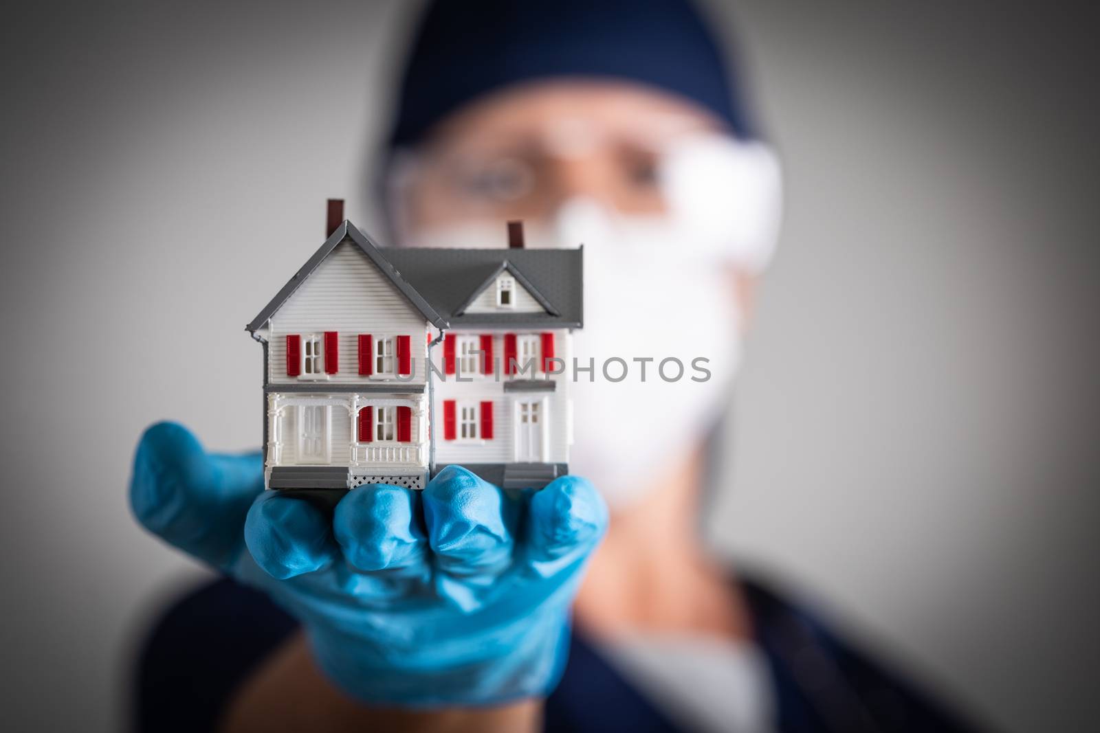 Female Doctor or Nurse Wearing Surgical Gloves Holding Model Home by Feverpitched