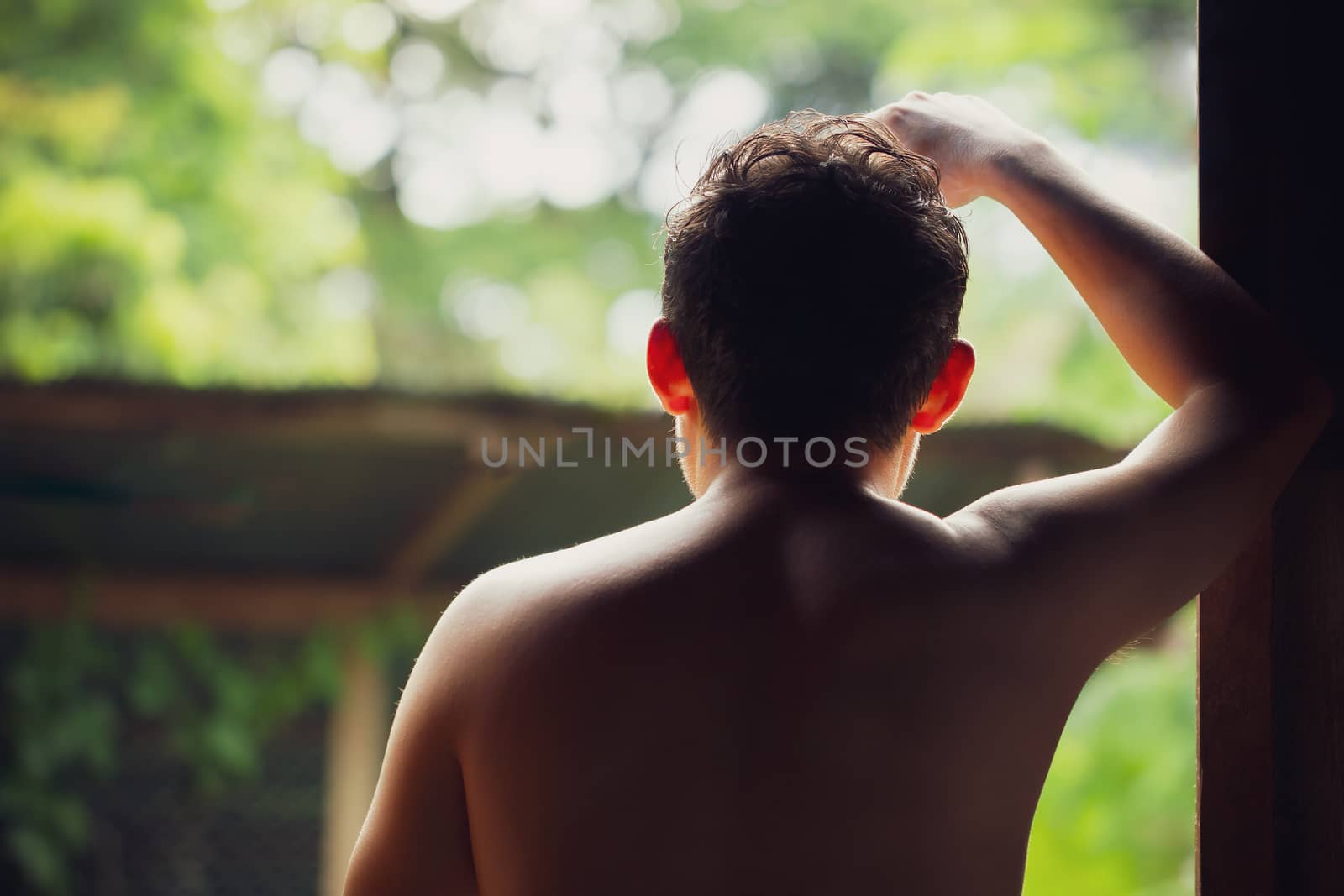 Depressed man standing beside windows and thinking. Closeup and copy space for text.