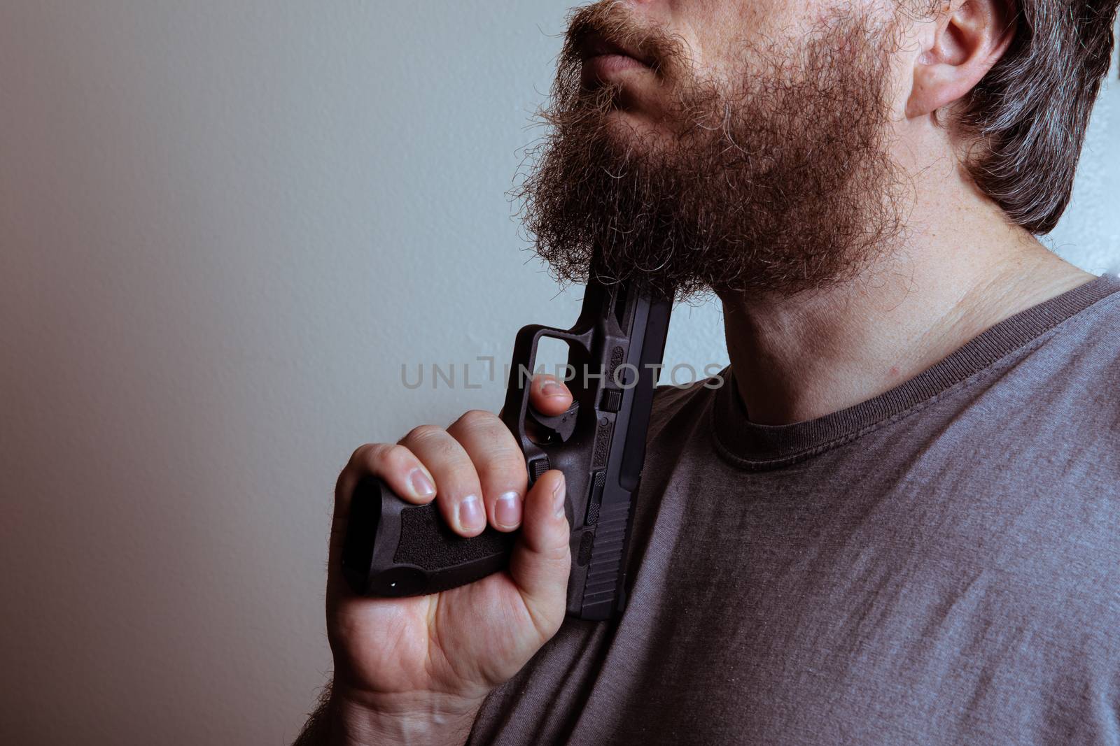 man holding a gun to his chin as he suffers from severe depression