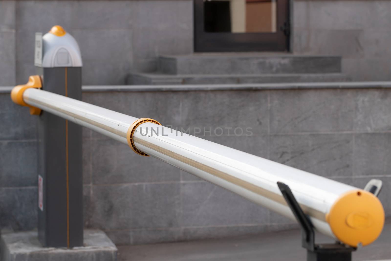 Automatic security metal barrier boom closed for stop and checking car entering to restricted area , placed at main entrance beside the road , selective focused, blurred background. Security concept or ban