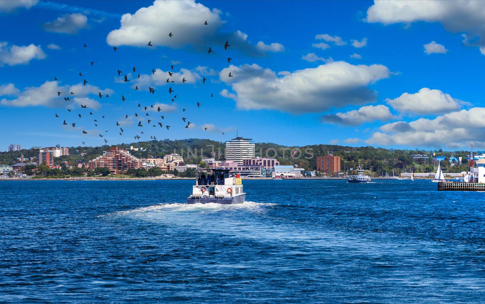 A full ferry pulling out of Halifax harbor and crossing blue water