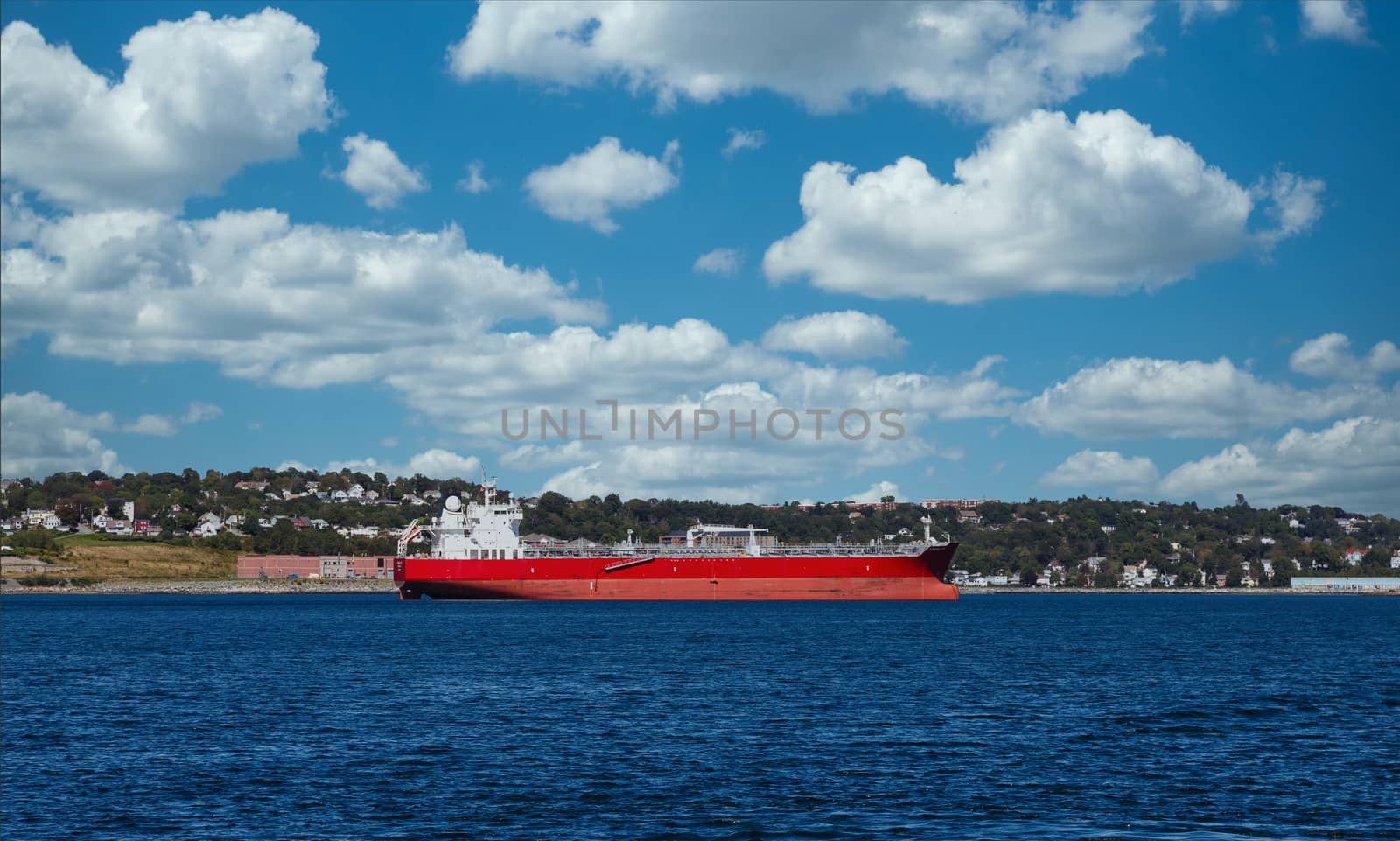 An empty red freighter in blue water of harbor