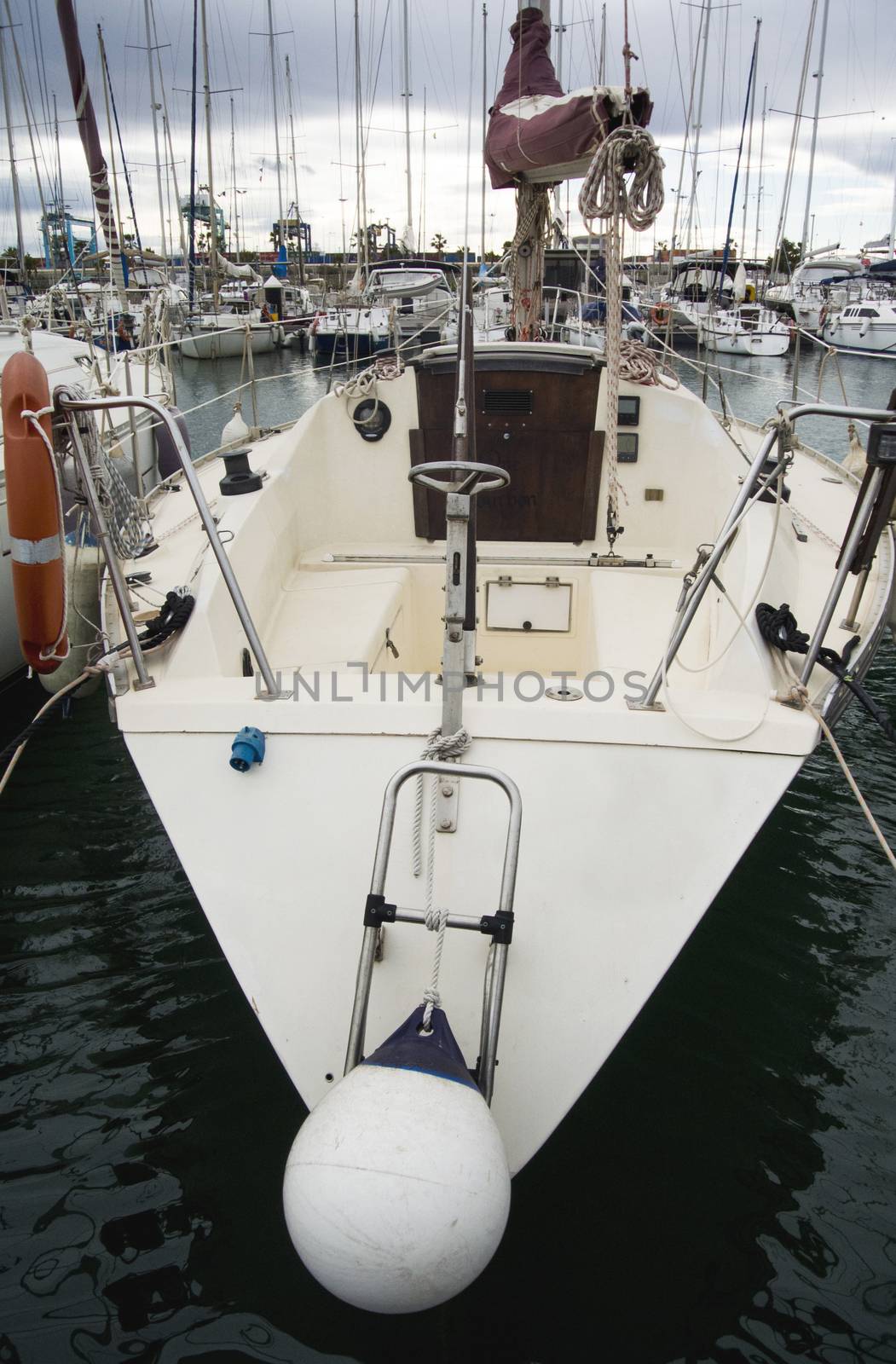 Boat In Valencia Port At Mediterranean Sea. Reflexion in the water. White yacht are in the Spanish port of Valencia in the beginning of spring. Cloudy sky