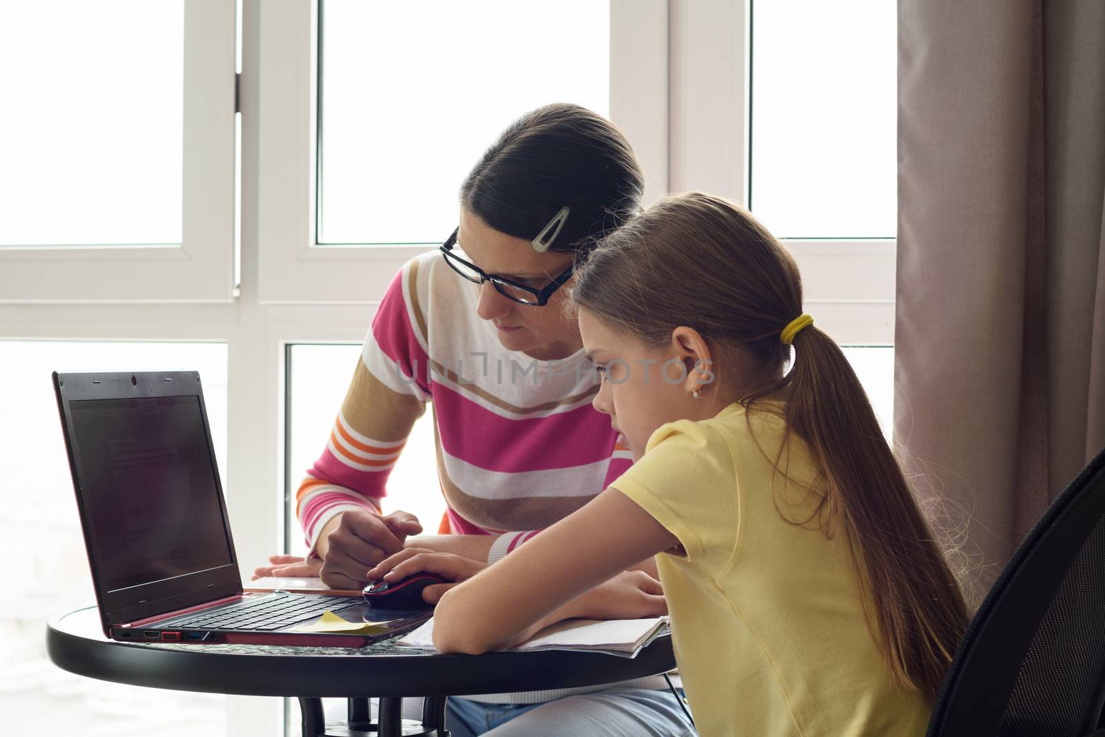 Mom and daughter are surfing the web together at home.