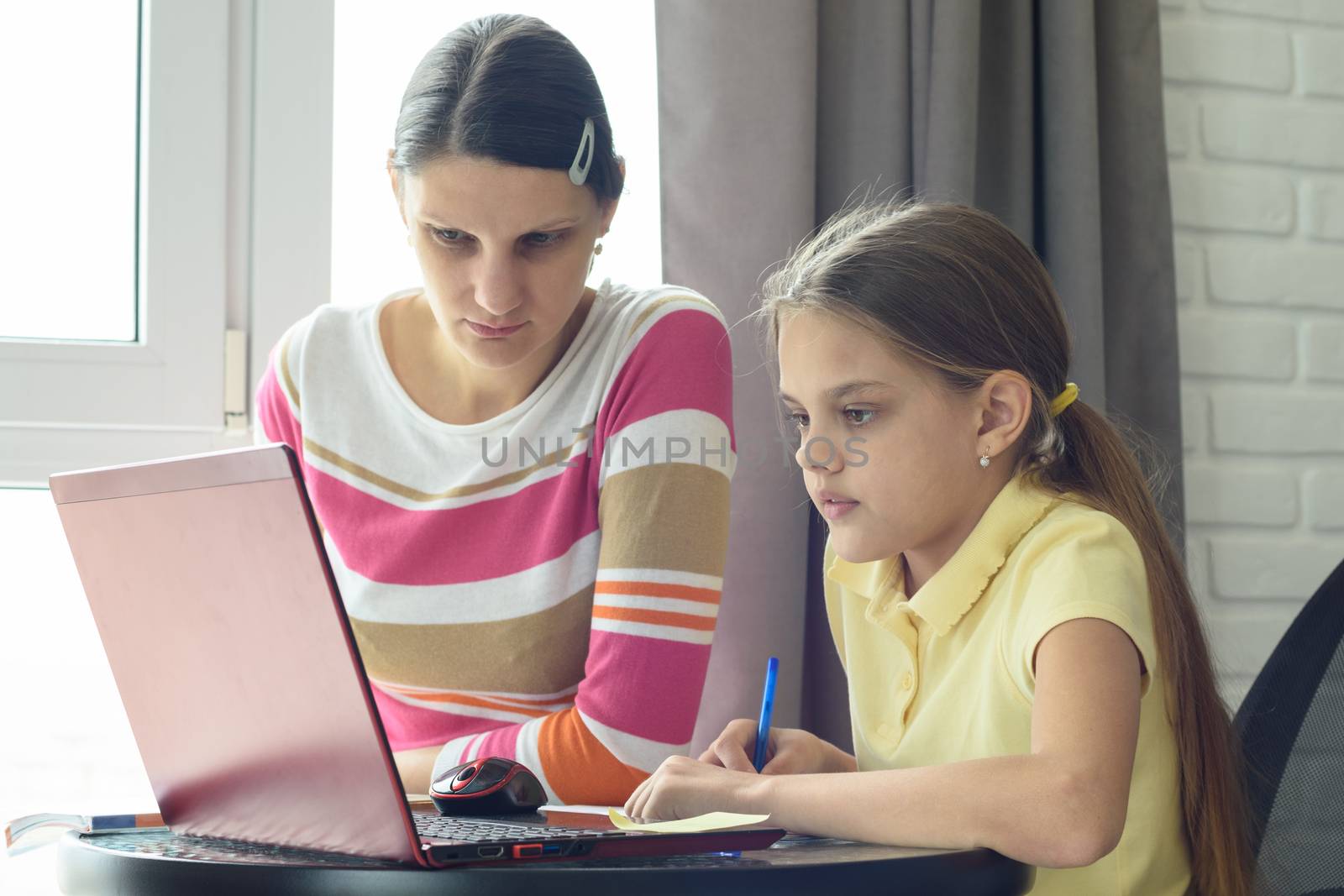 Mom and daughter solve homework using online distance learning