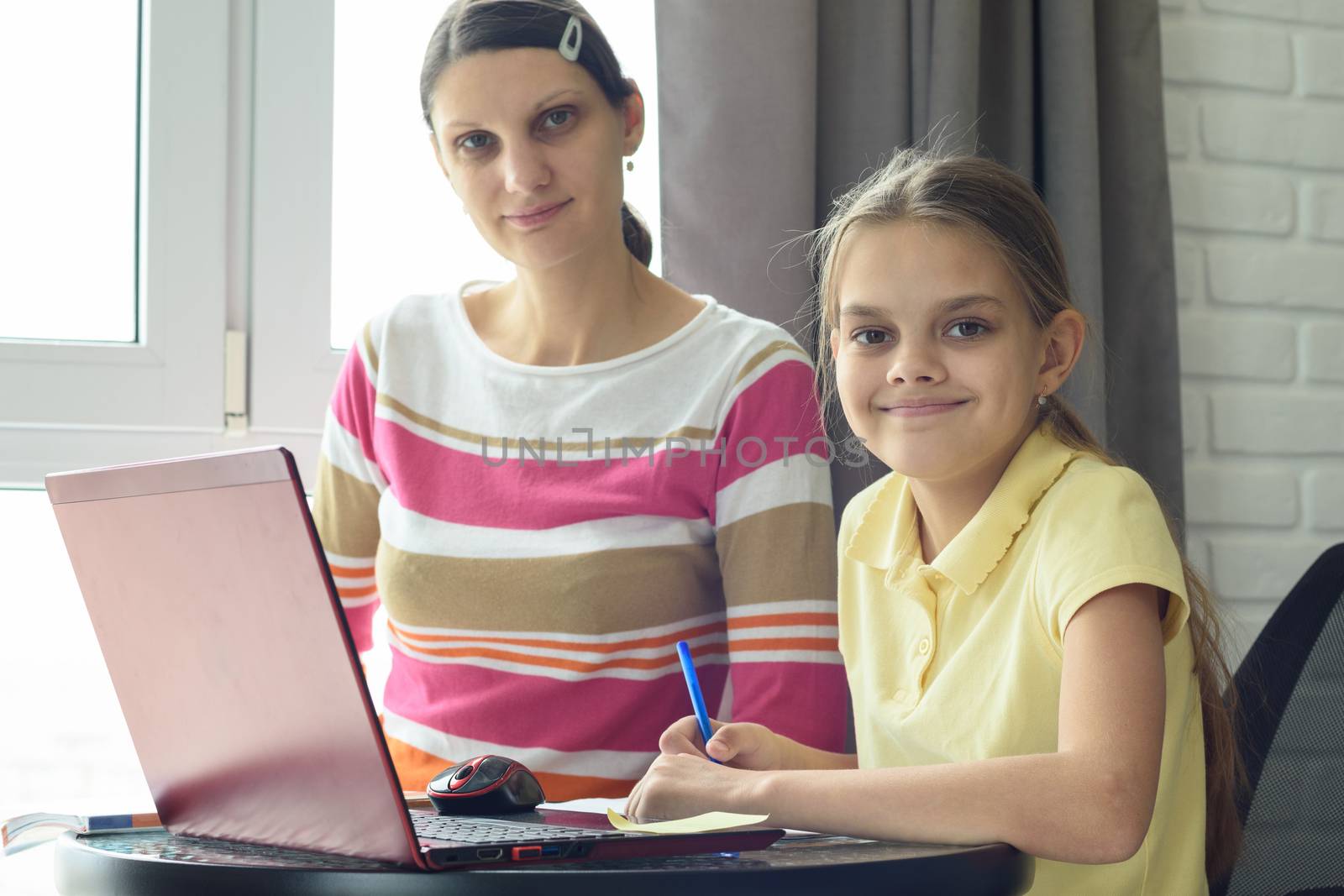 Happy girl doing homework with mom looked in frame