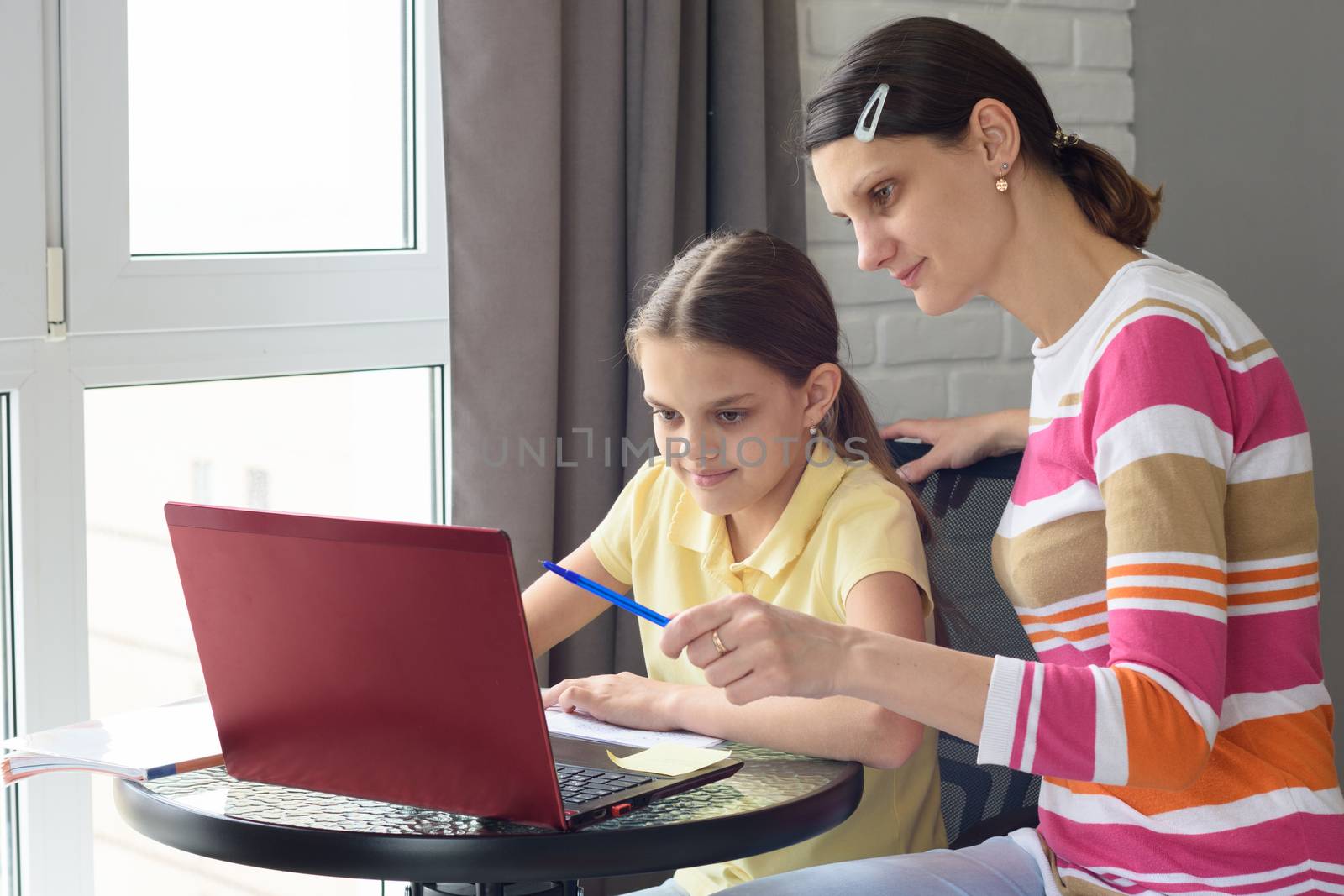 A tutor helps a girl learn online through the Internet