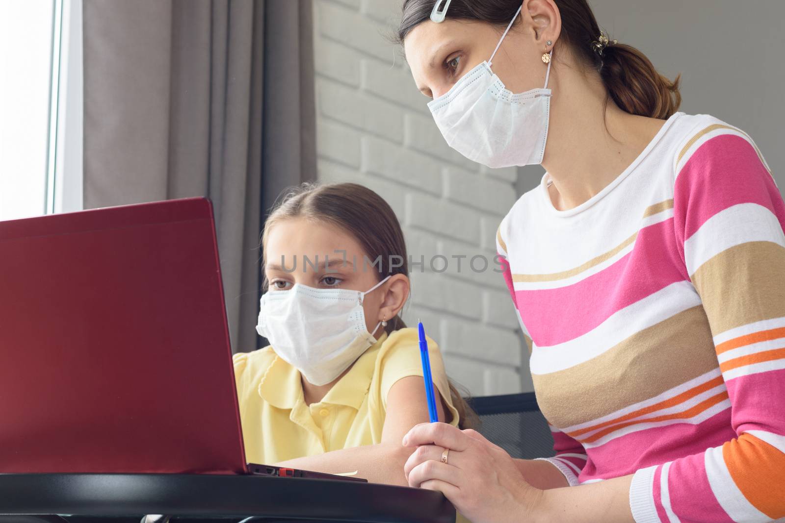 Girl and tutor in medical masks study remotely online