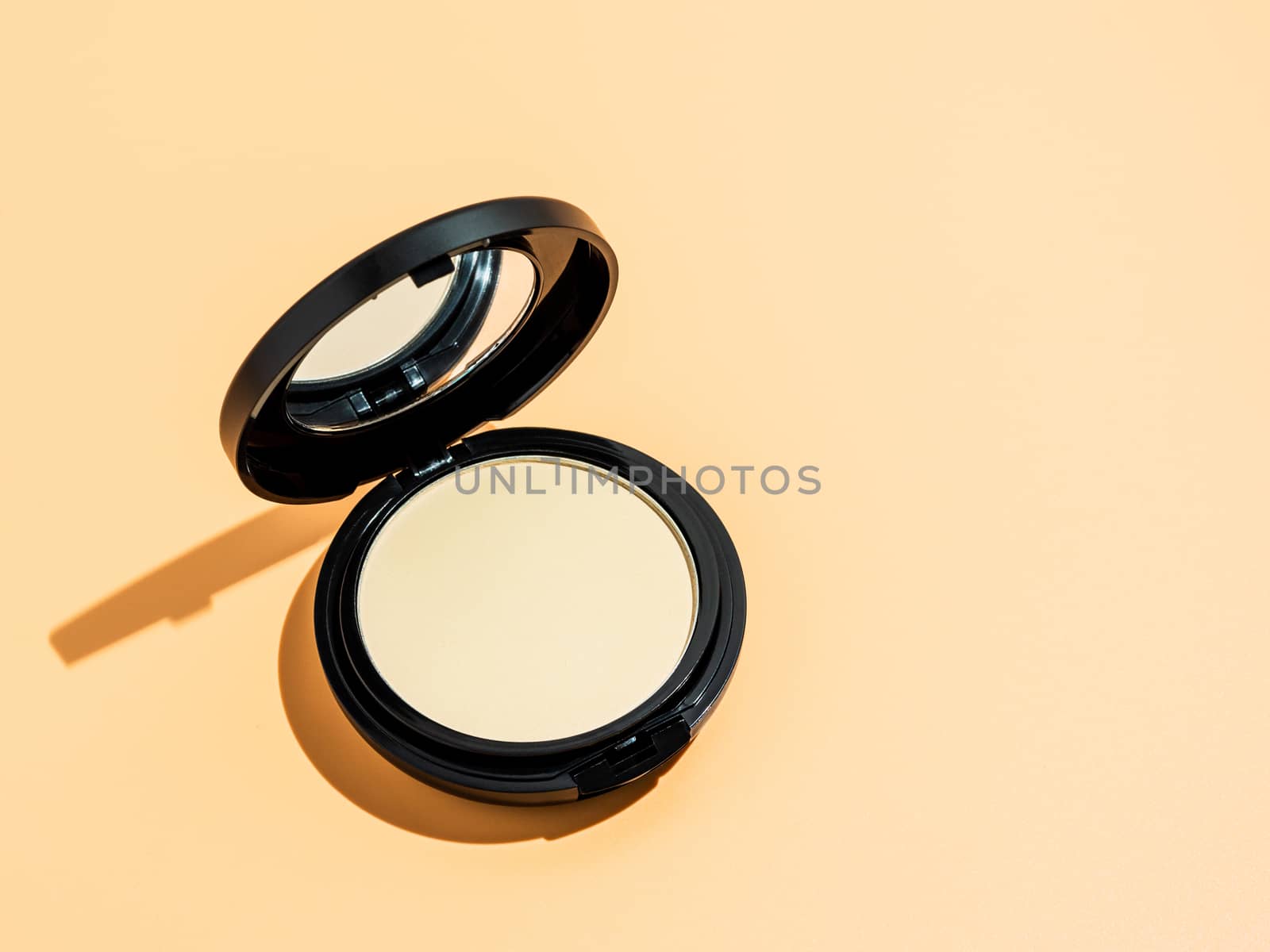 Compact powder on yellow background, copy space by fascinadora