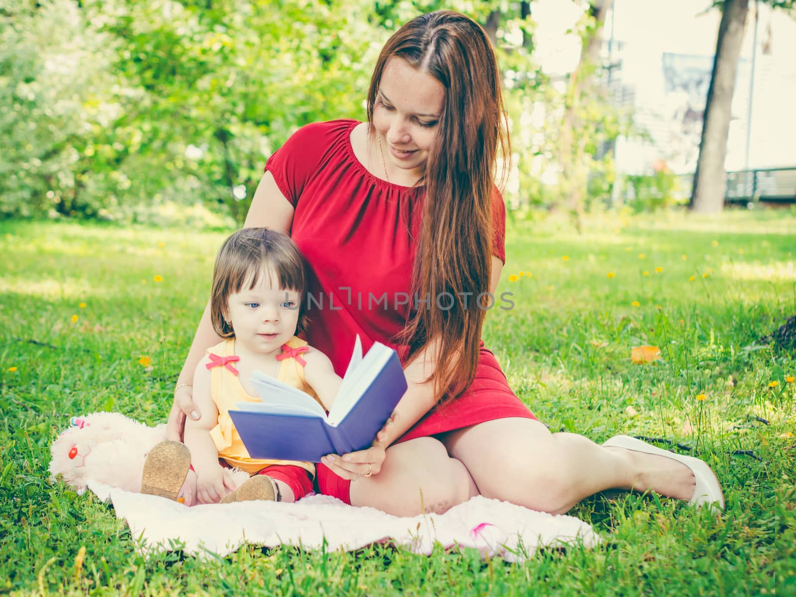Mother and daughter reading book outdoors by fascinadora