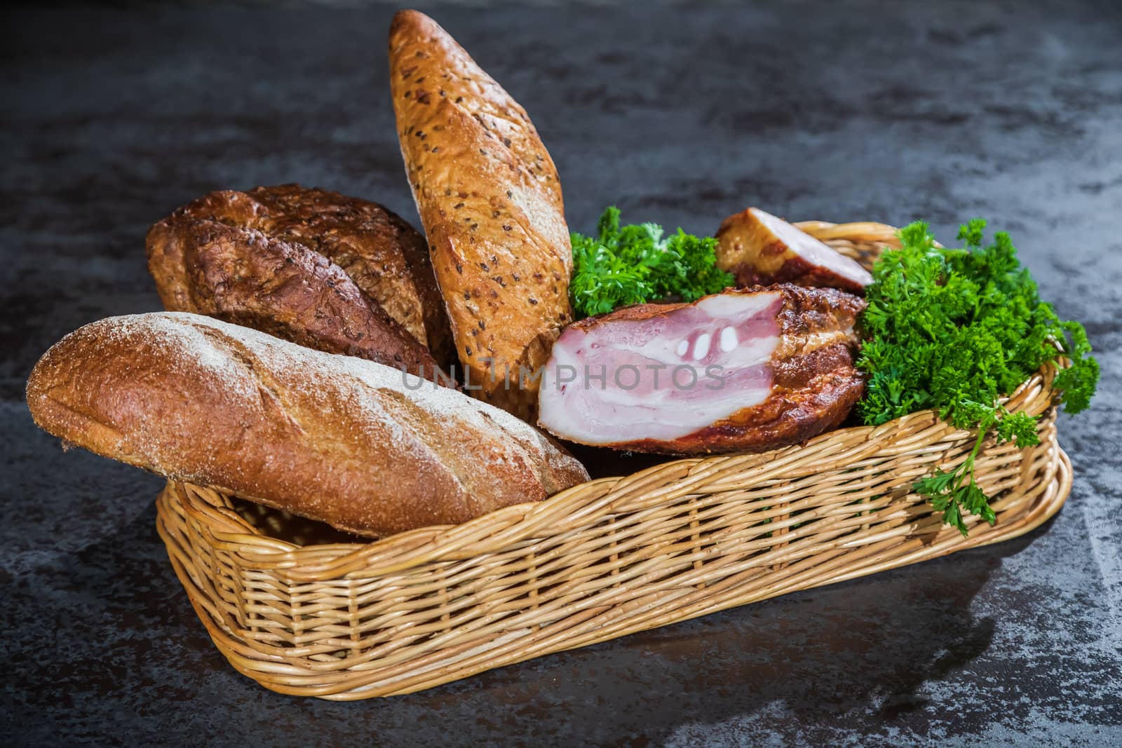 Still life. Bread and smoked meat in a braided basket on the table.