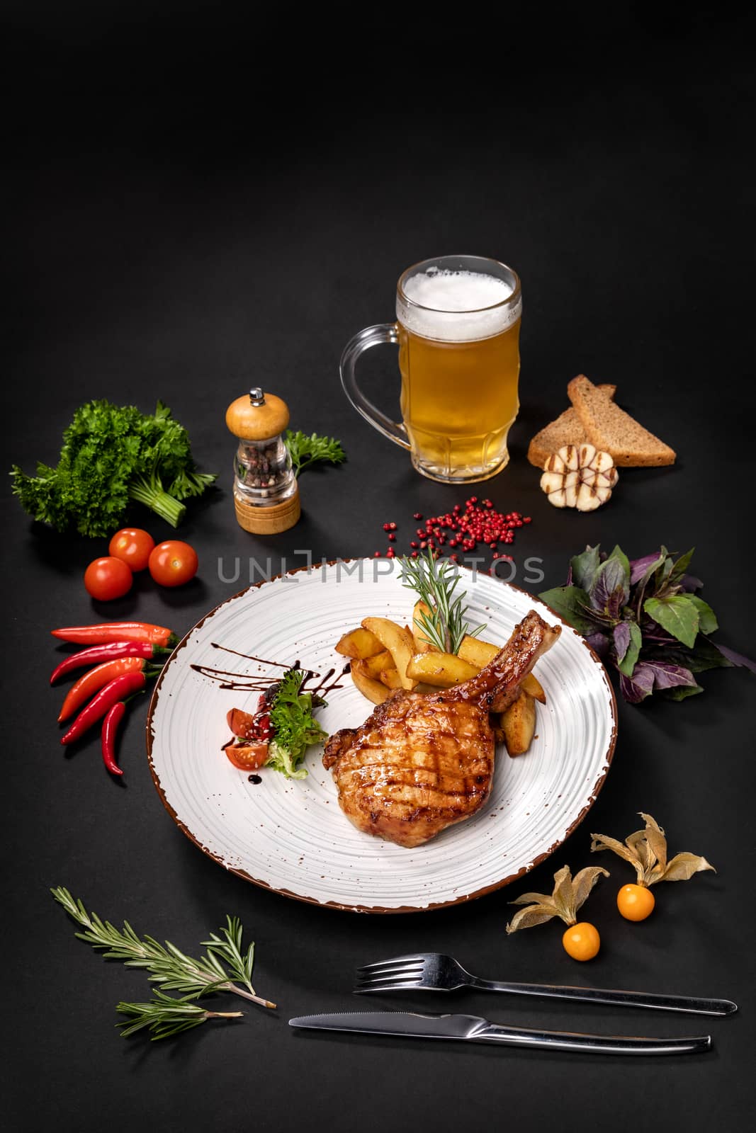 An antrecot of pork on a plate next to a bottle of beer on a black background